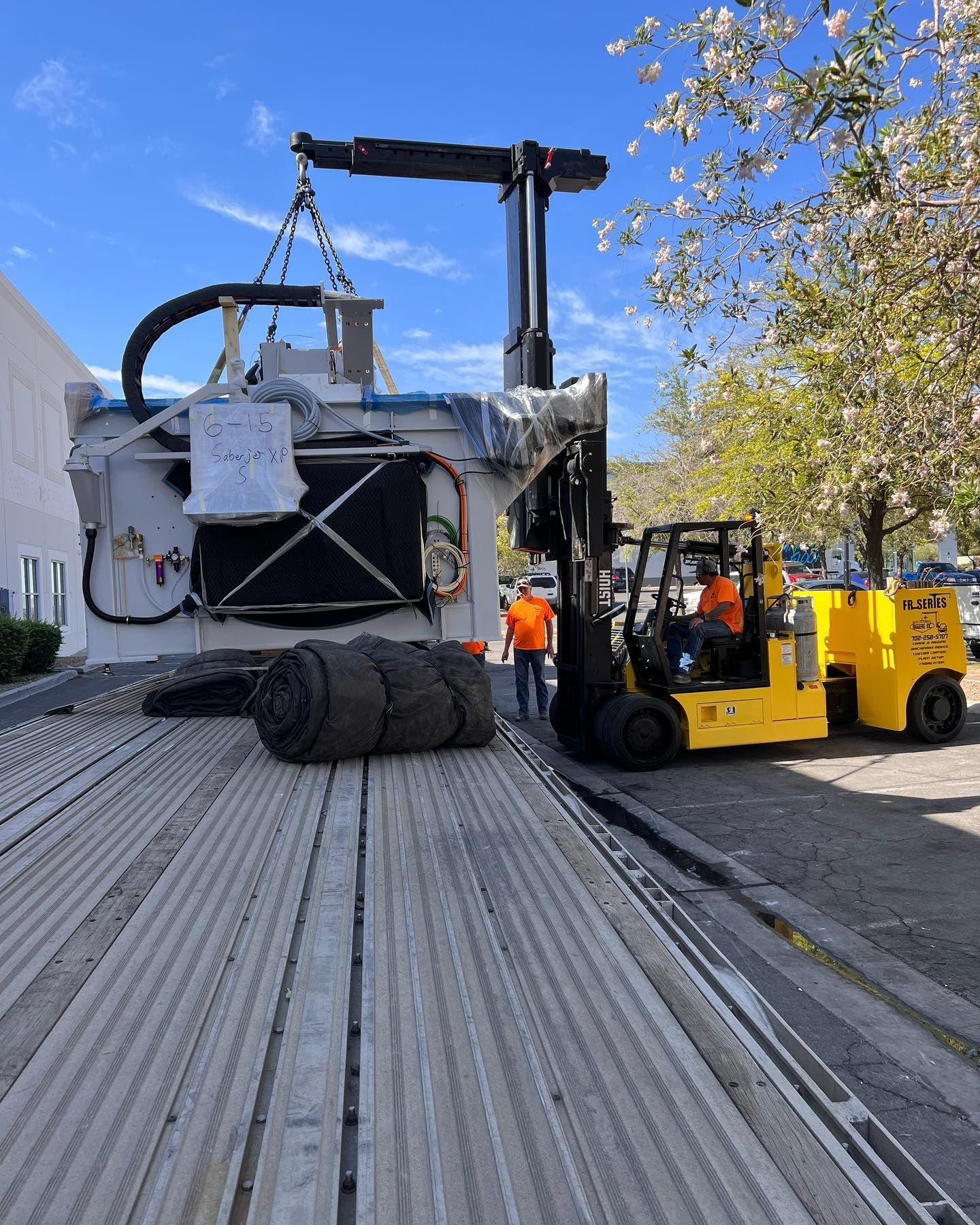 A yellow forklift is lifting a large piece of equipment
