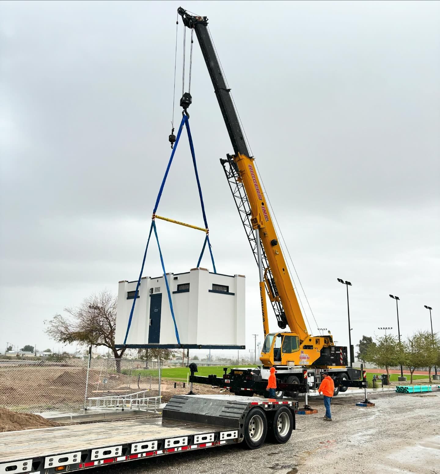 A crane is lifting a container on a trailer