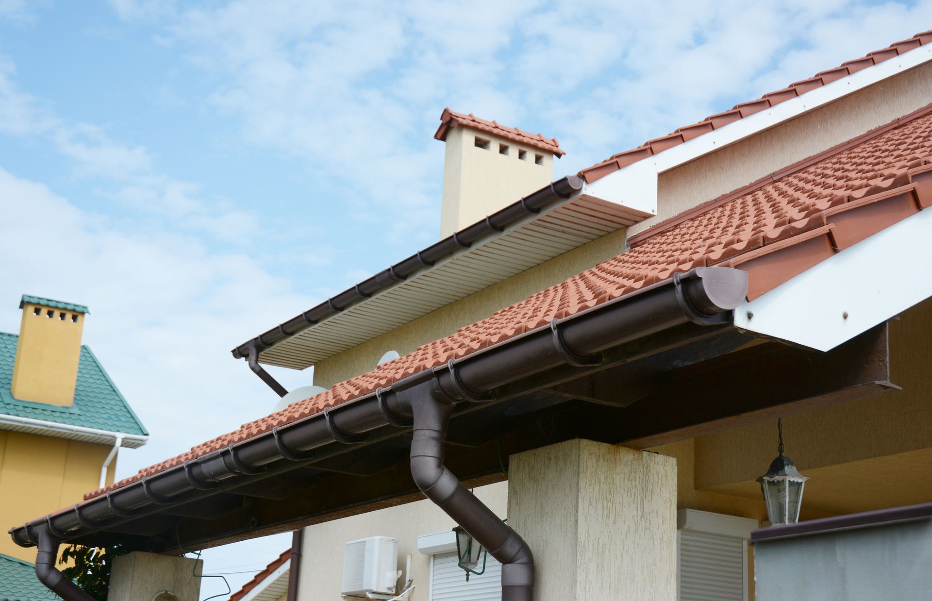 A house with a brown gutter and a chimney on the roof.