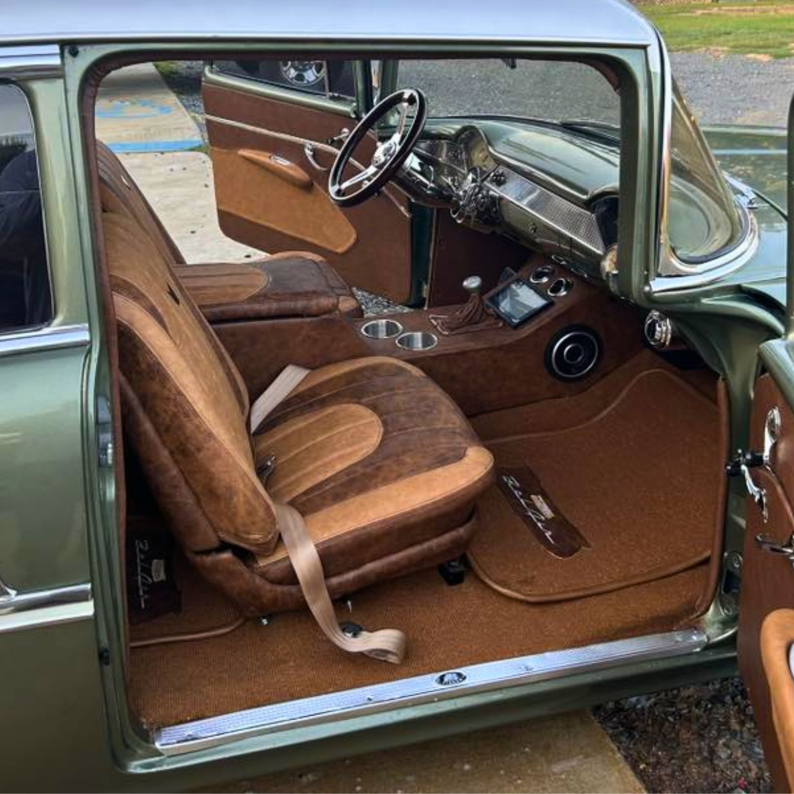 A classic vintage car interior featuring brown custom leather bucket seats, matching trim, and an aftermarket console.