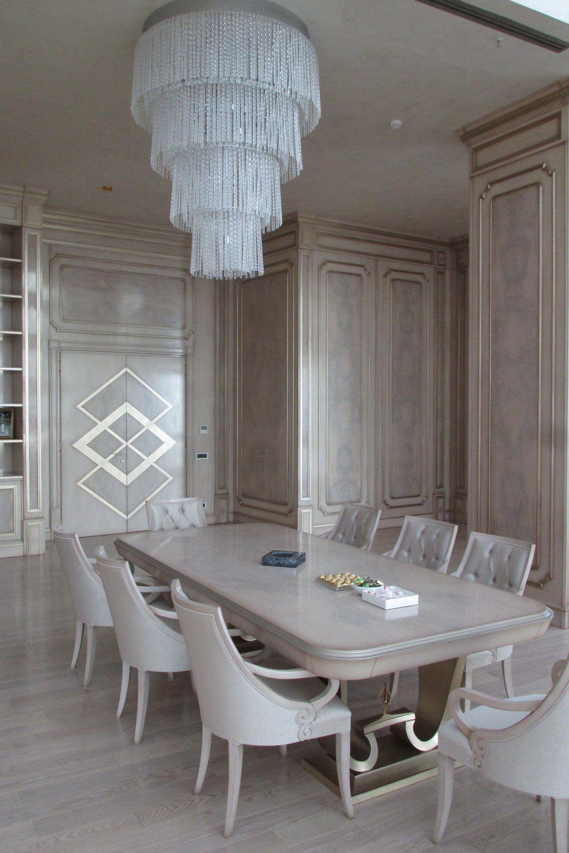 Una sala da pranzo con un lungo tavolo e sedie e un lampadario appeso al soffitto.