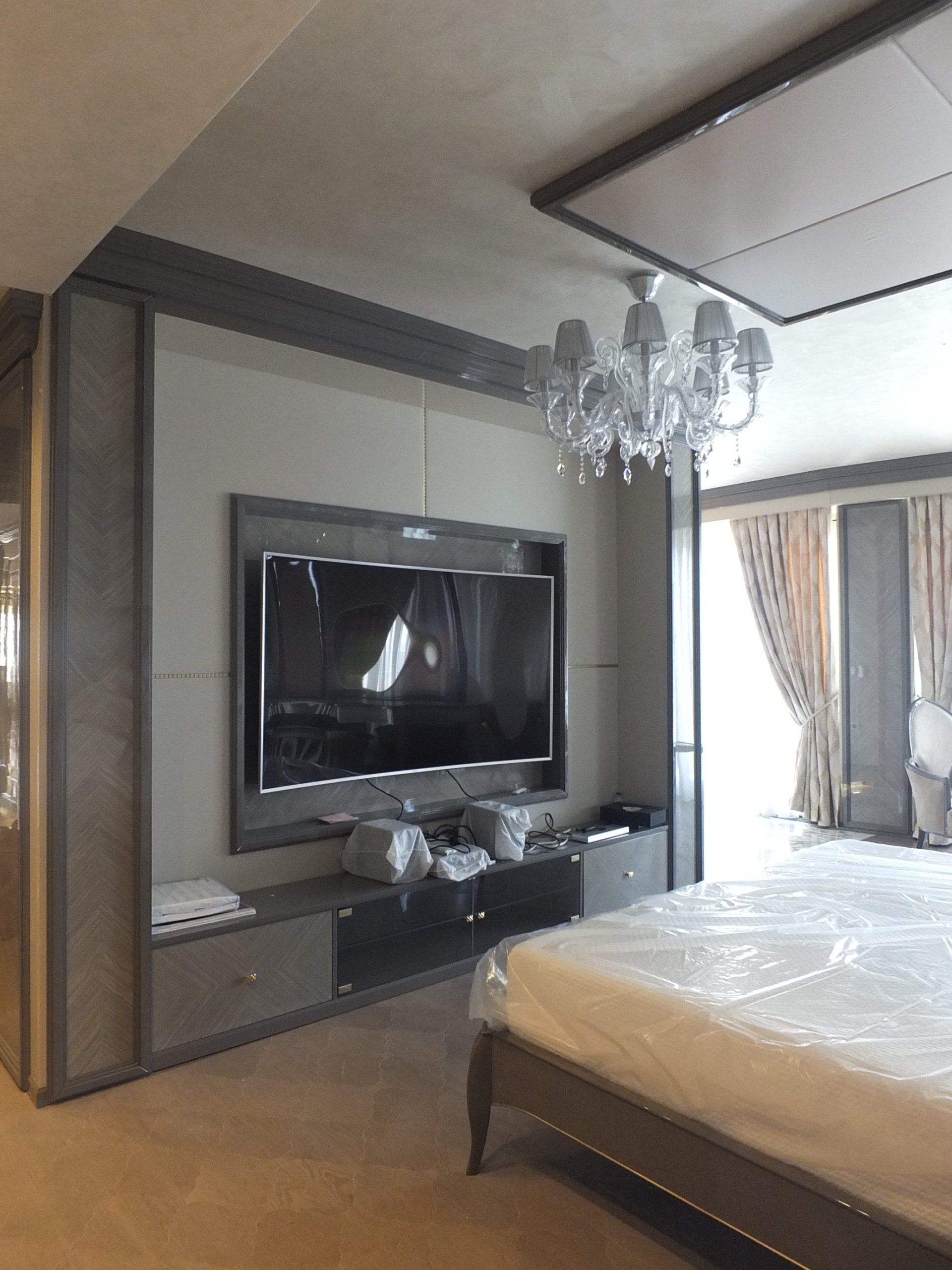 Una camera da letto con una grande tv a schermo piatto sulla parete sopra il letto
