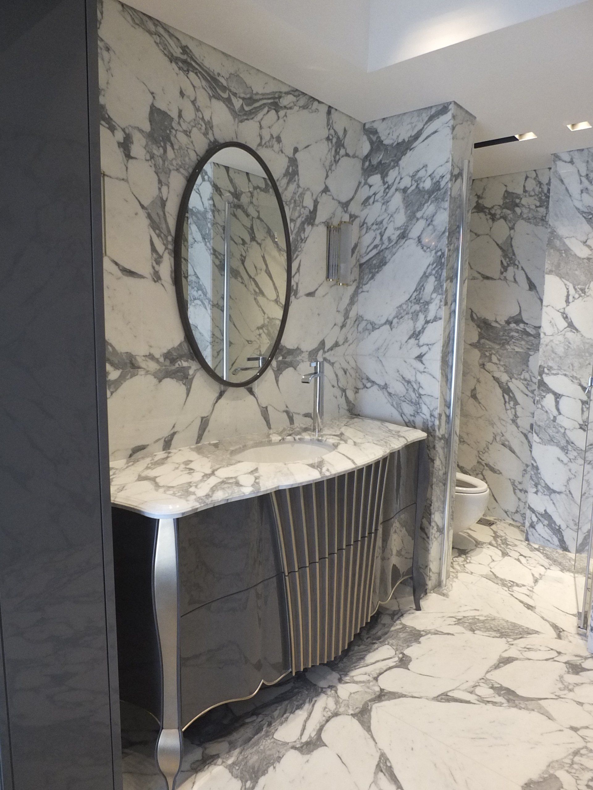 un bagno con pareti in marmo e lavabo e specchio