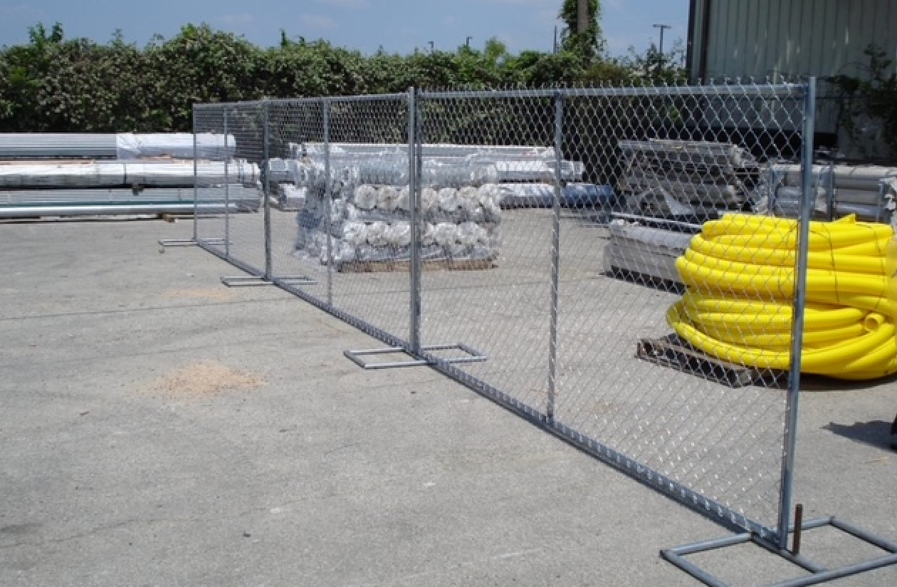 A chain link fence surrounds a lot of yellow pipes