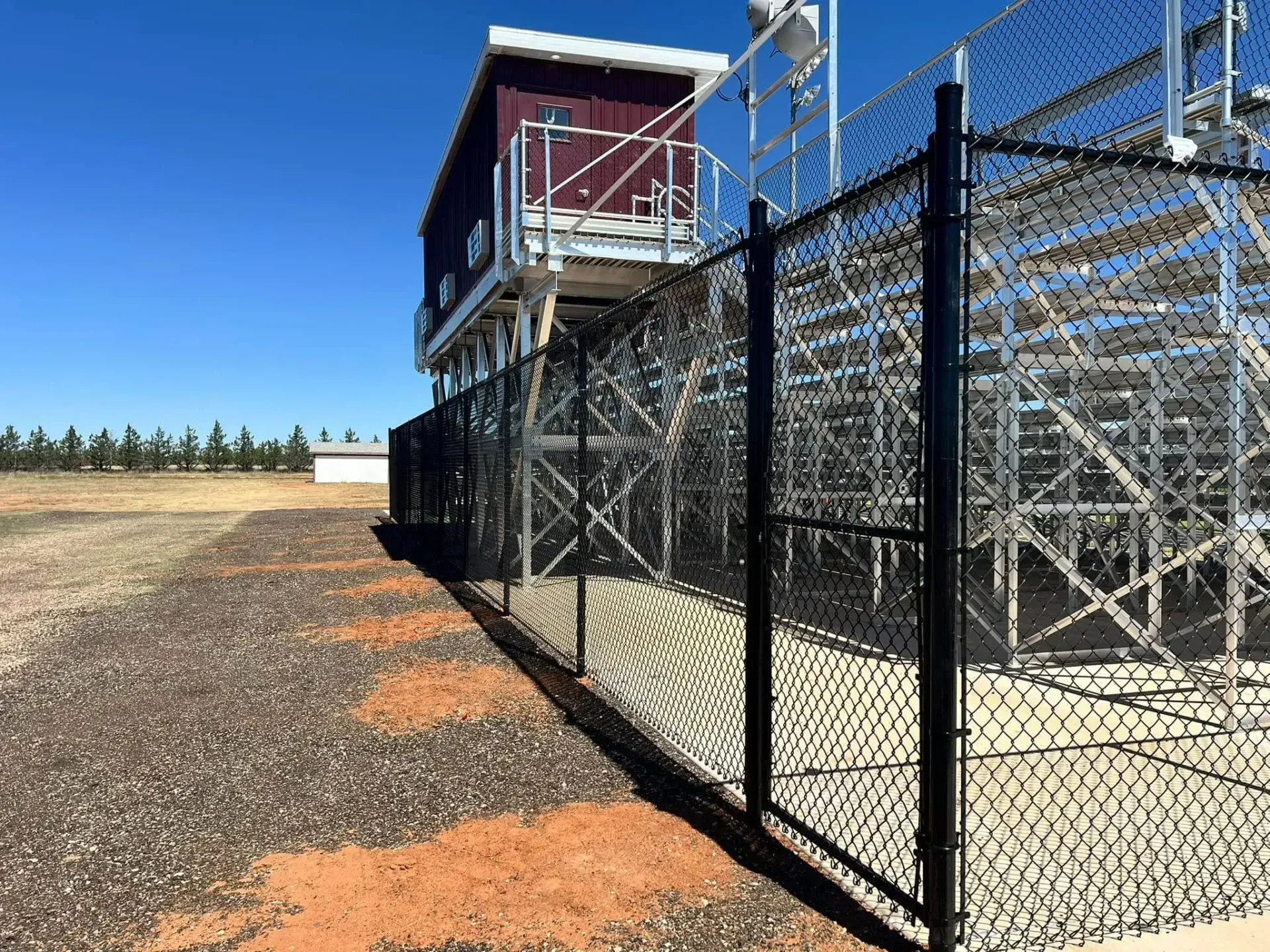 A chain link fence surrounds a stadium with bleachers.