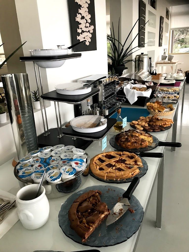 Buffet con vari tipi di dolci e yogurt su un lungo tavolo in una sala luminosa.