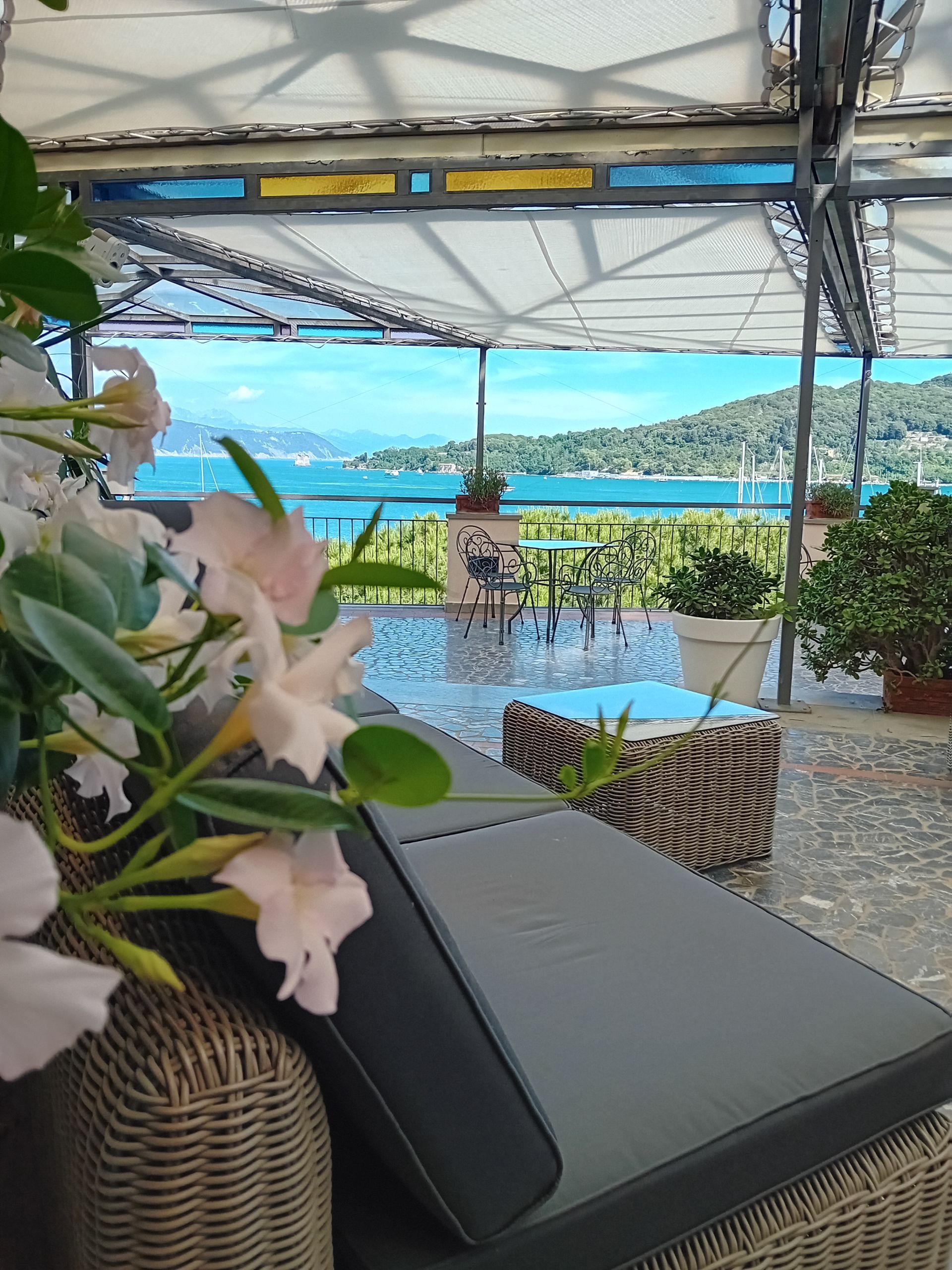 Rilassante patio esterno con vista sull'oceano, fiori e sedia a sdraio.