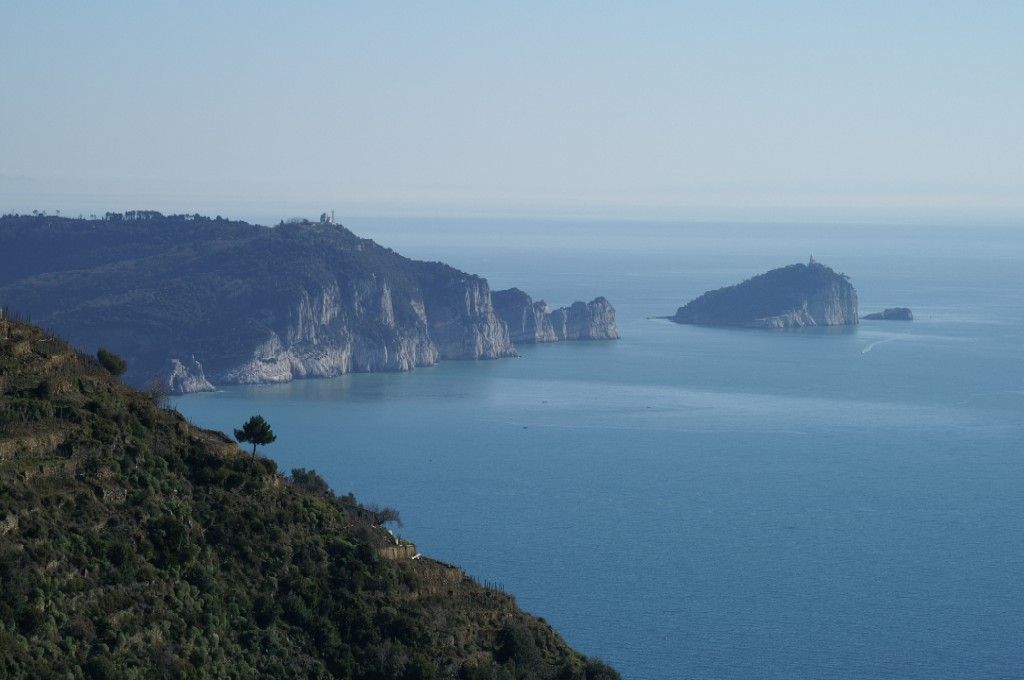 Vista sull'oceano azzurro con scogliere rocciose e una piccola isola sotto un cielo limpido.