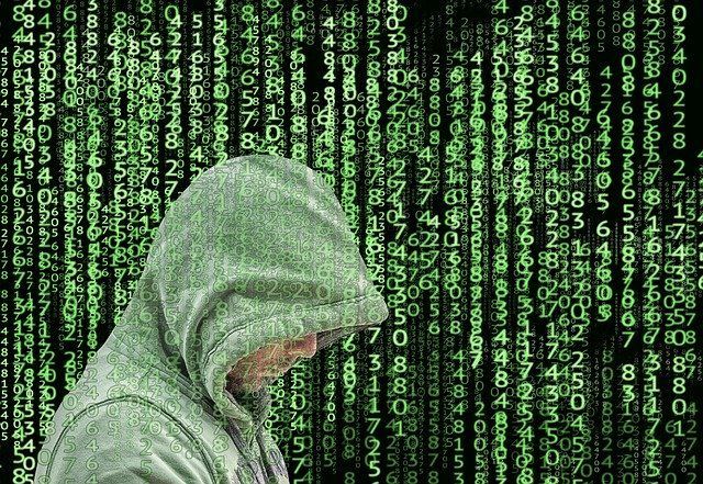 A man in a hoodie is standing in front of a matrix background.