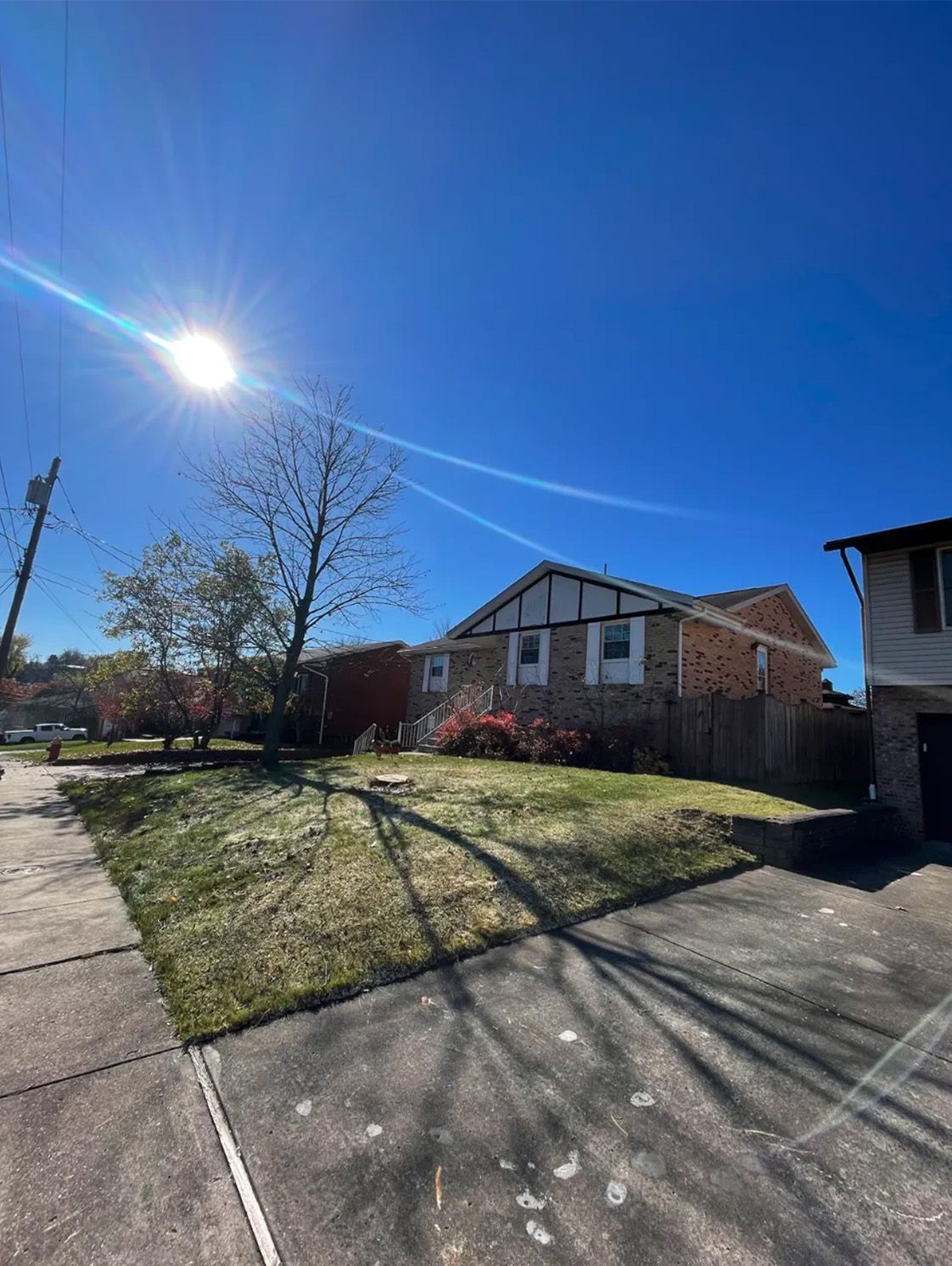 The sun is shining brightly on a brick house in a residential area.