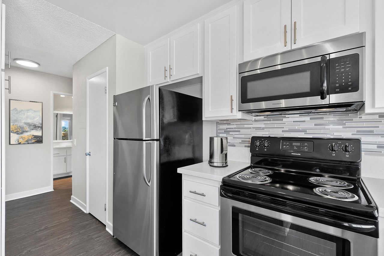 A kitchen with stainless steel appliances and white cabinets.
