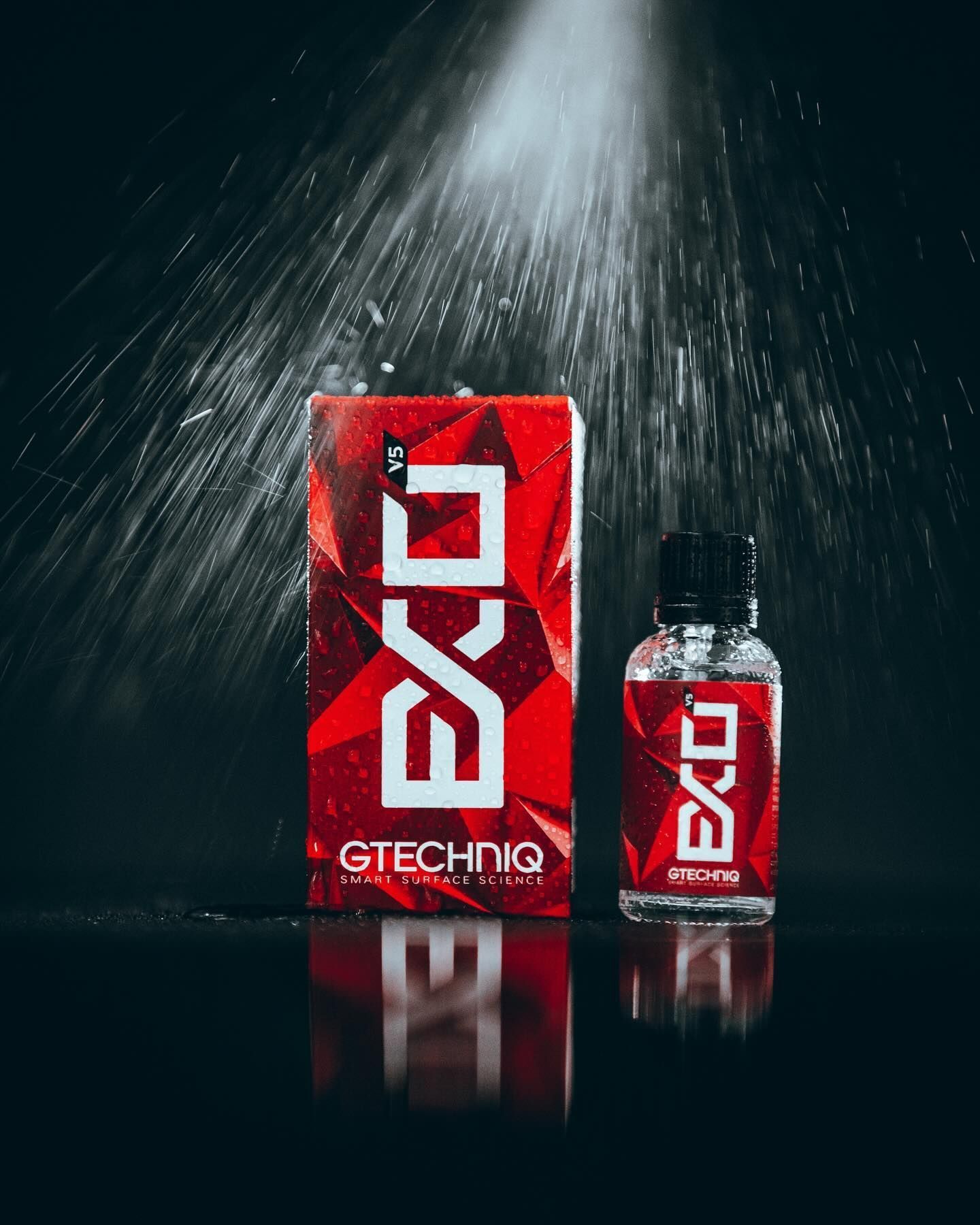 Red GTCHNIG box and matching bottle on a dark reflective surface with water spray above.