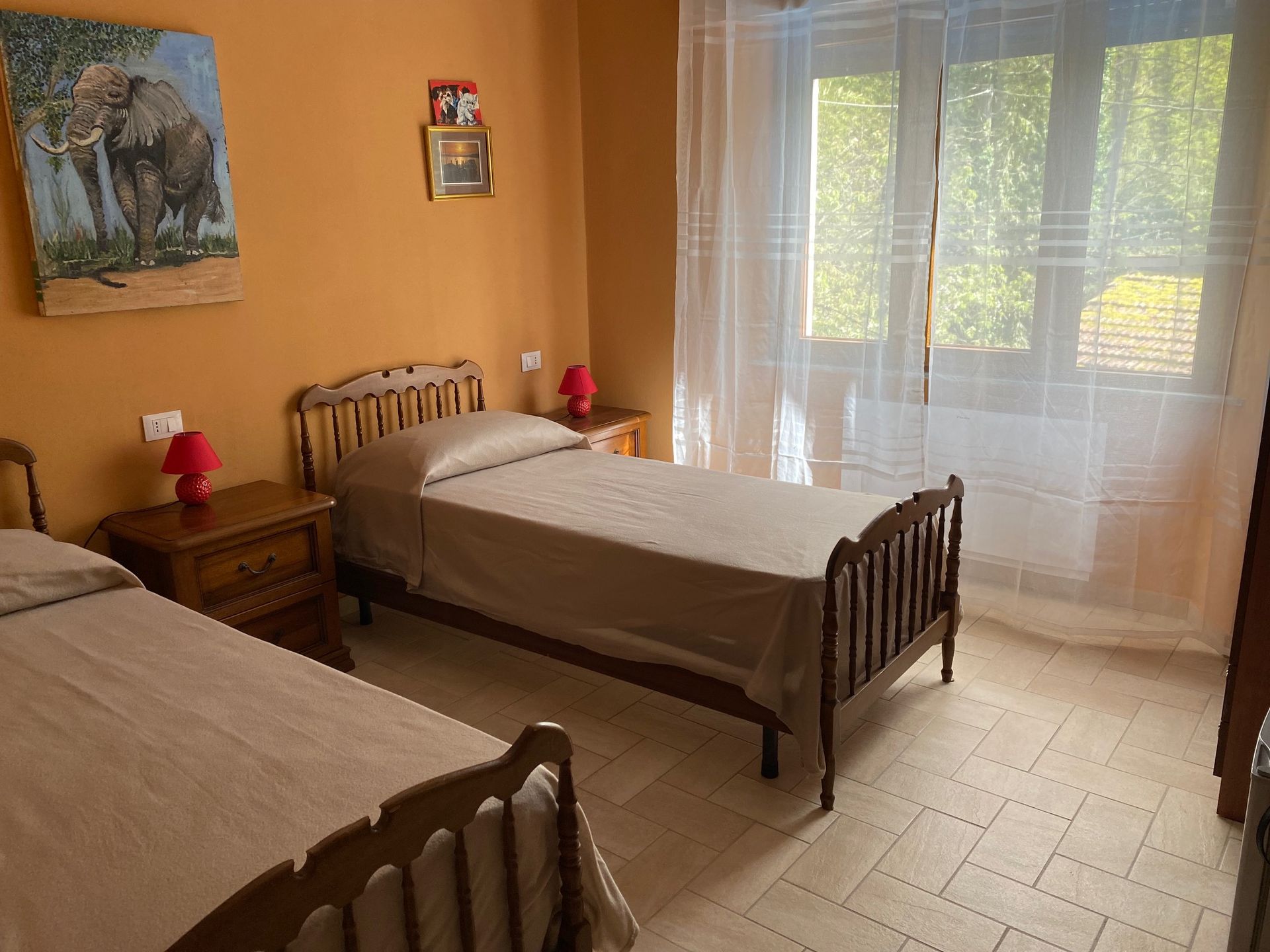 A room with two beds and a painting of an elephant on the wall.