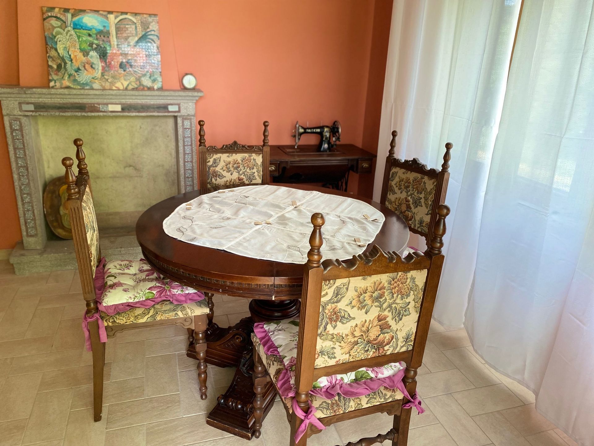 A dining room with a table and chairs and a sewing machine.