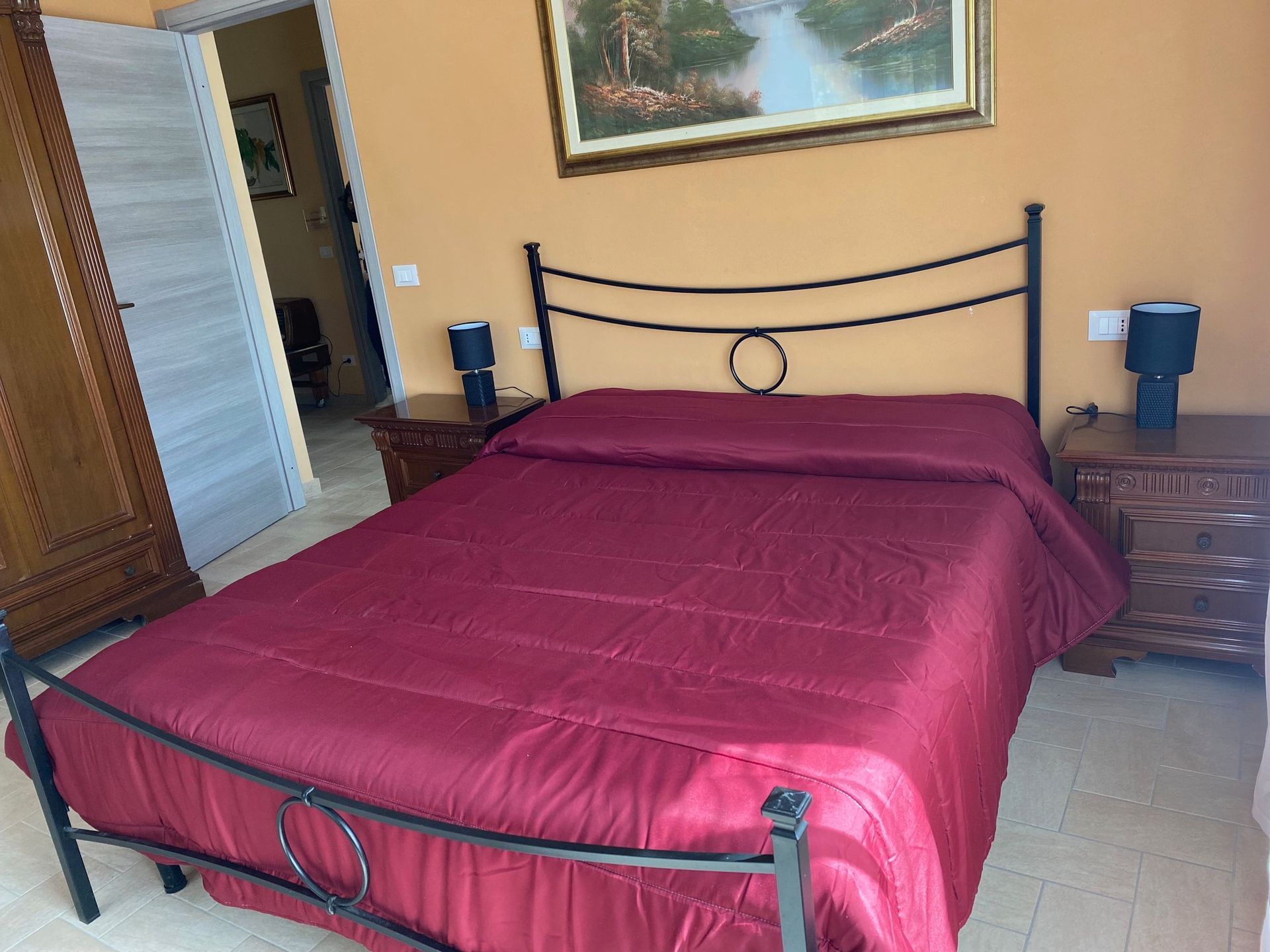 A room with a bed and a painting on the wall.