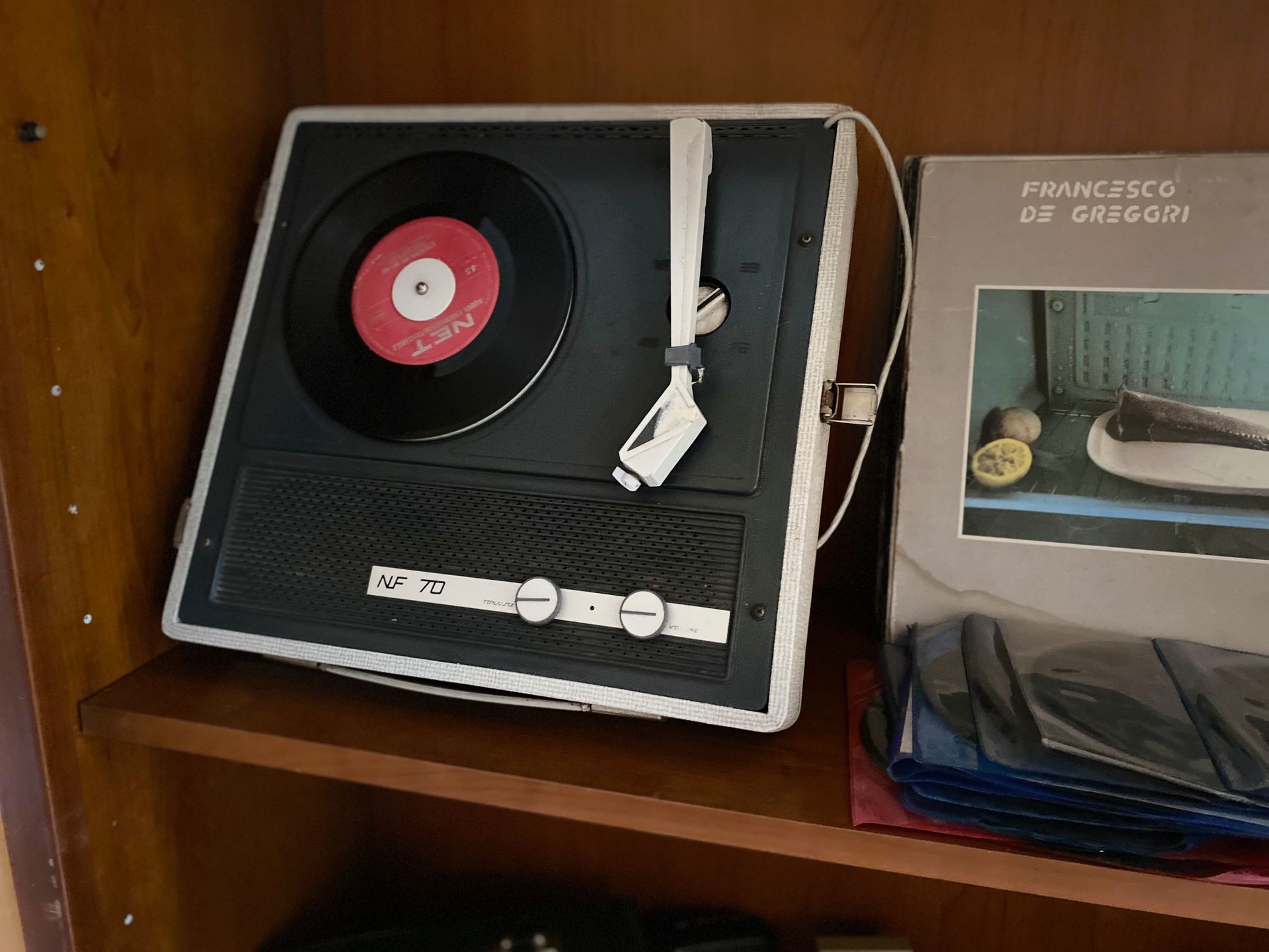 A record player is sitting on a wooden shelf.