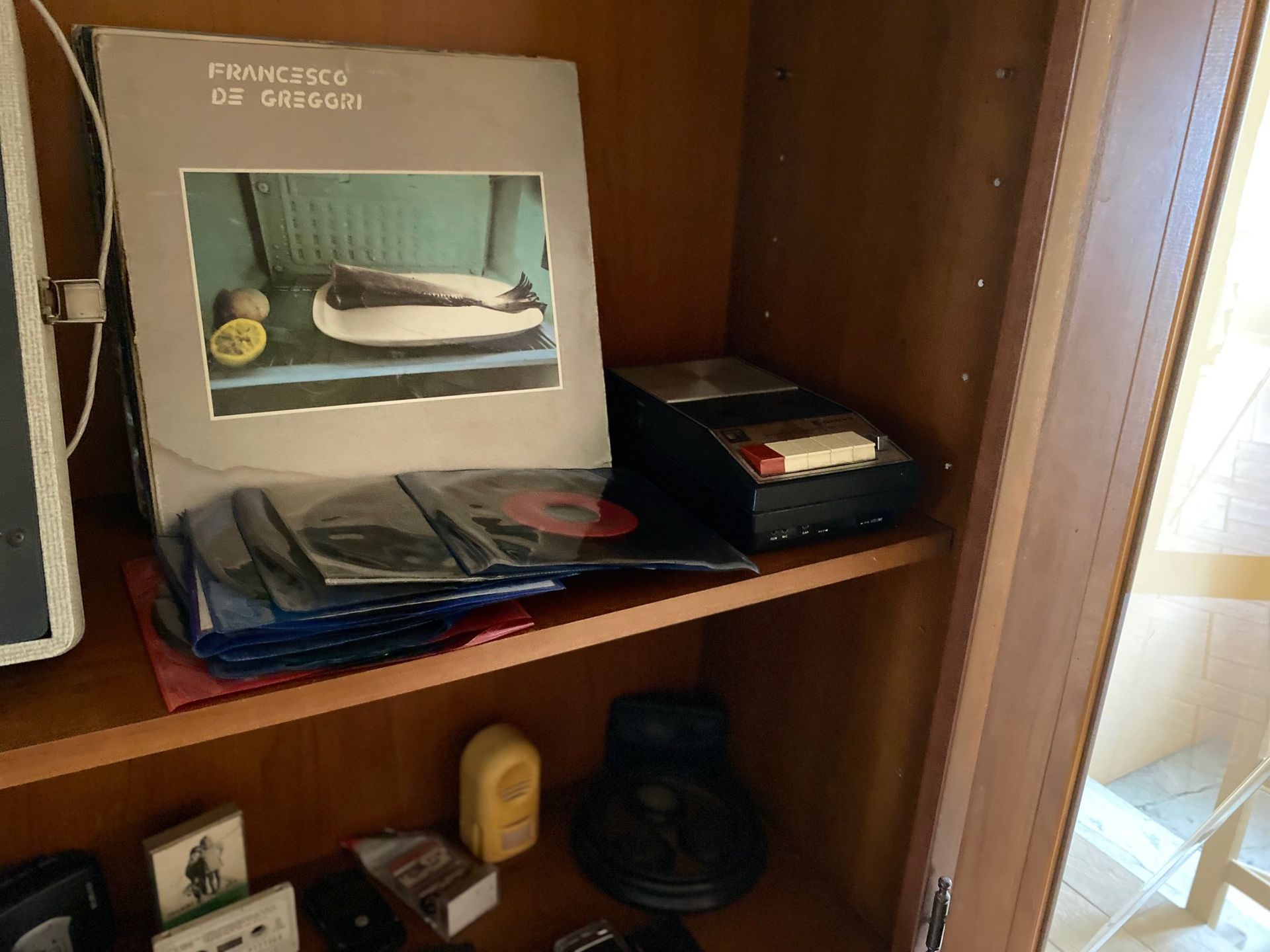 A record player is sitting on a wooden shelf.
