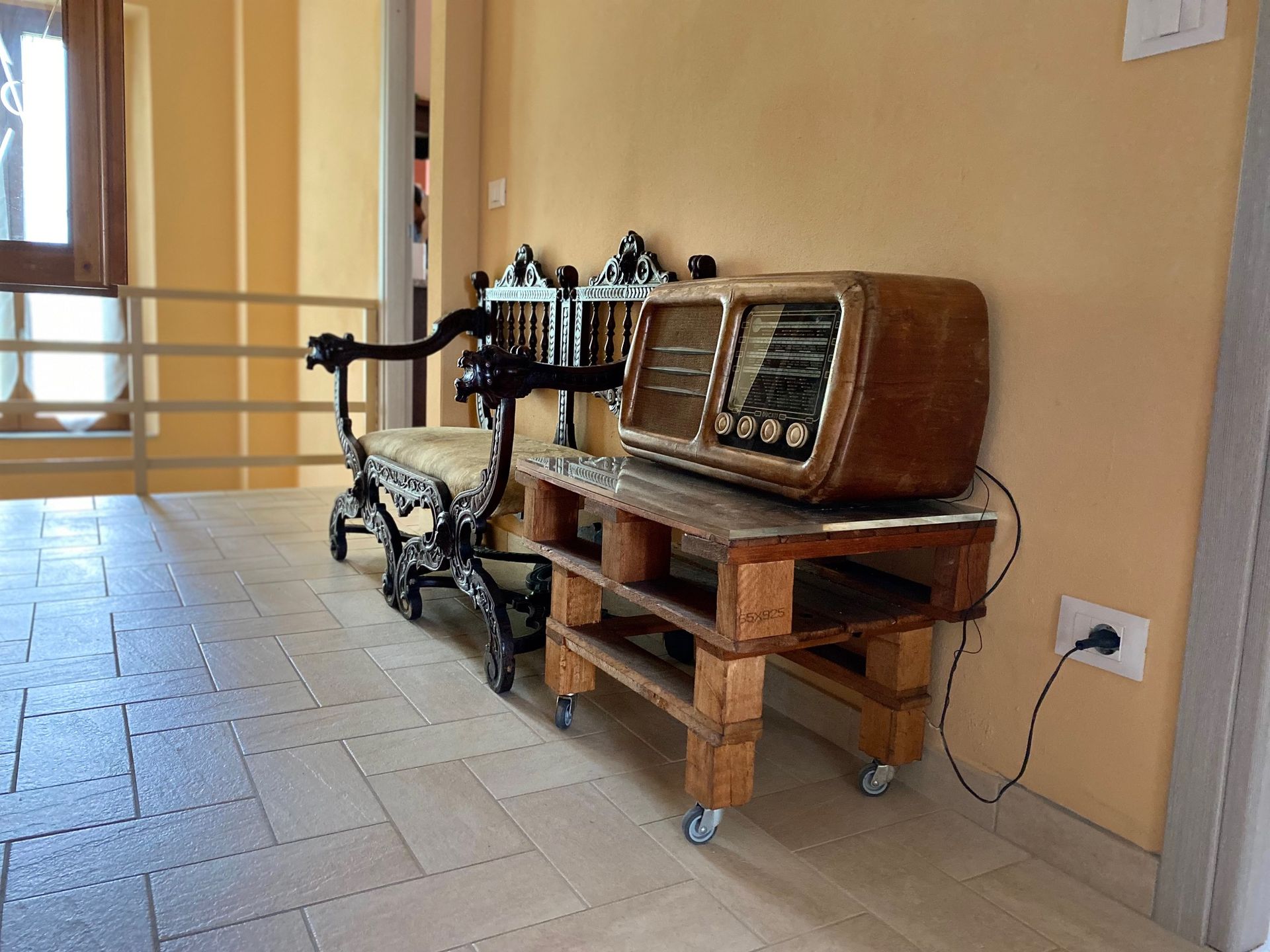 On a wooden table next to a chair, an old radio is placed.