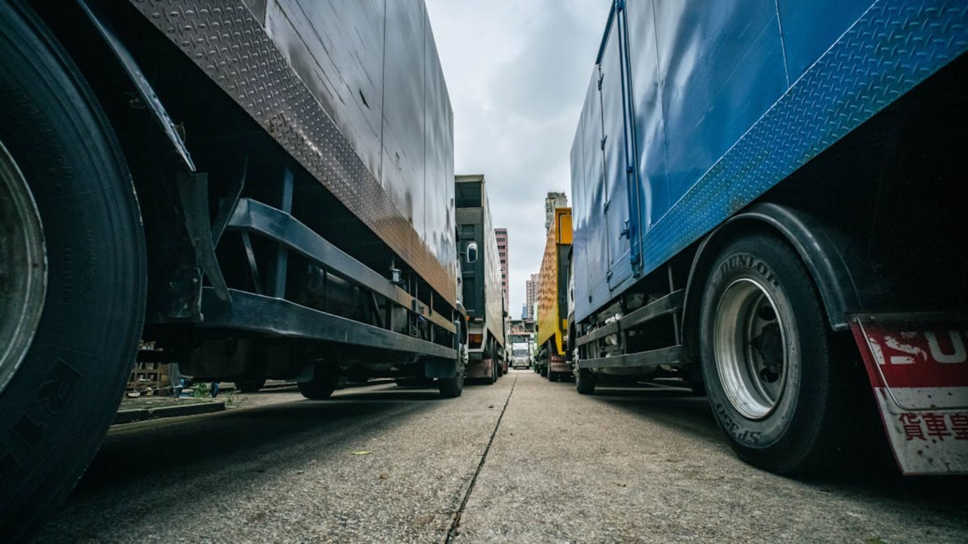 Dos camiones grandes estacionados uno cerca del otro en una carretera de concreto, perspectiva en ángulo.