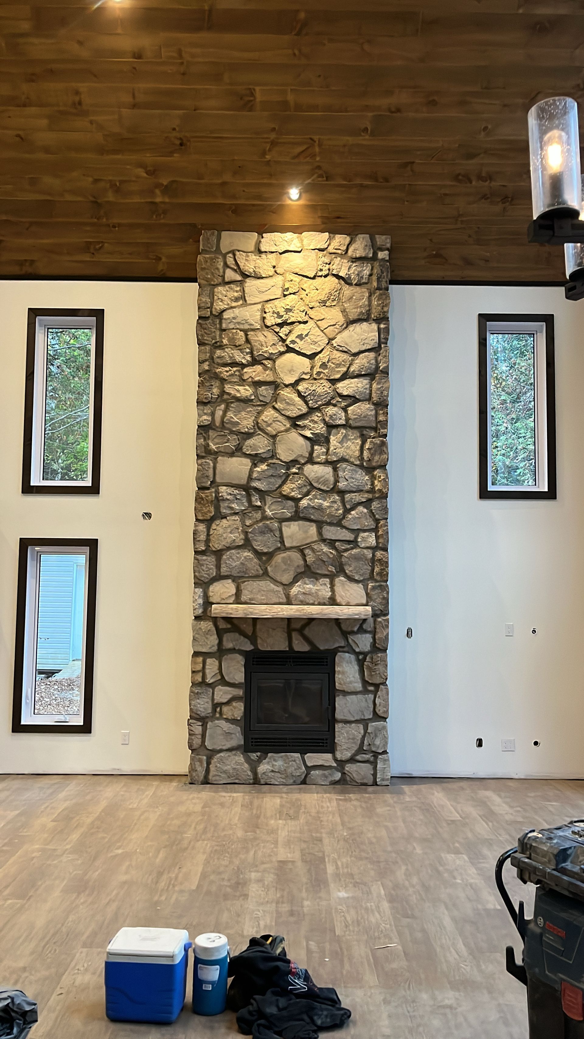 Un séjour avec une cheminée en pierre et deux fenêtres.