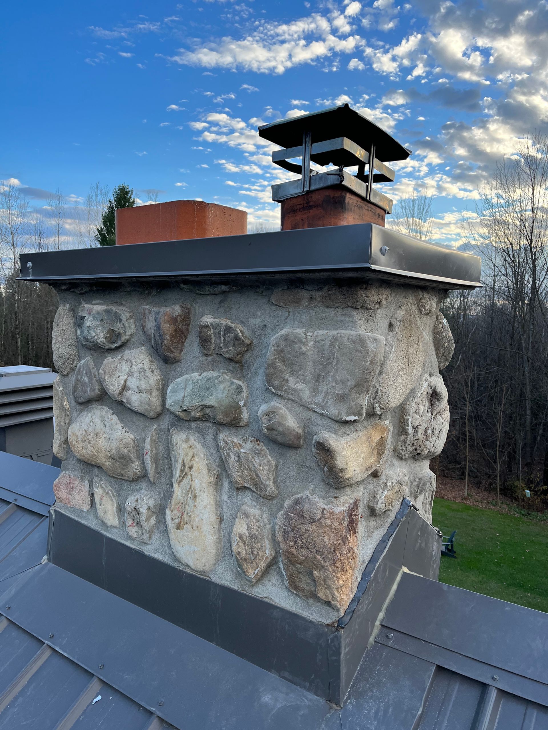 Une cheminée en pierre sur un toit en métal.