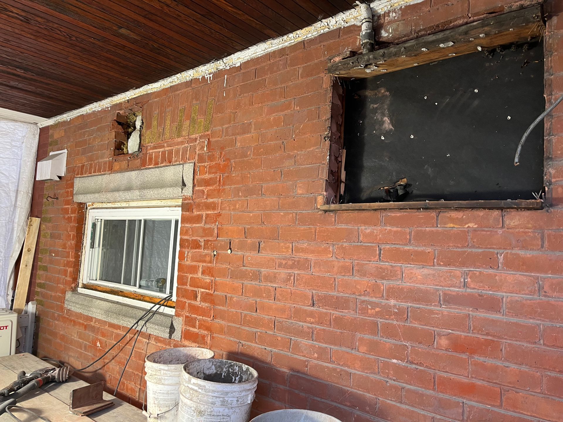 Un mur de briques avec deux fenêtres et des seaux.