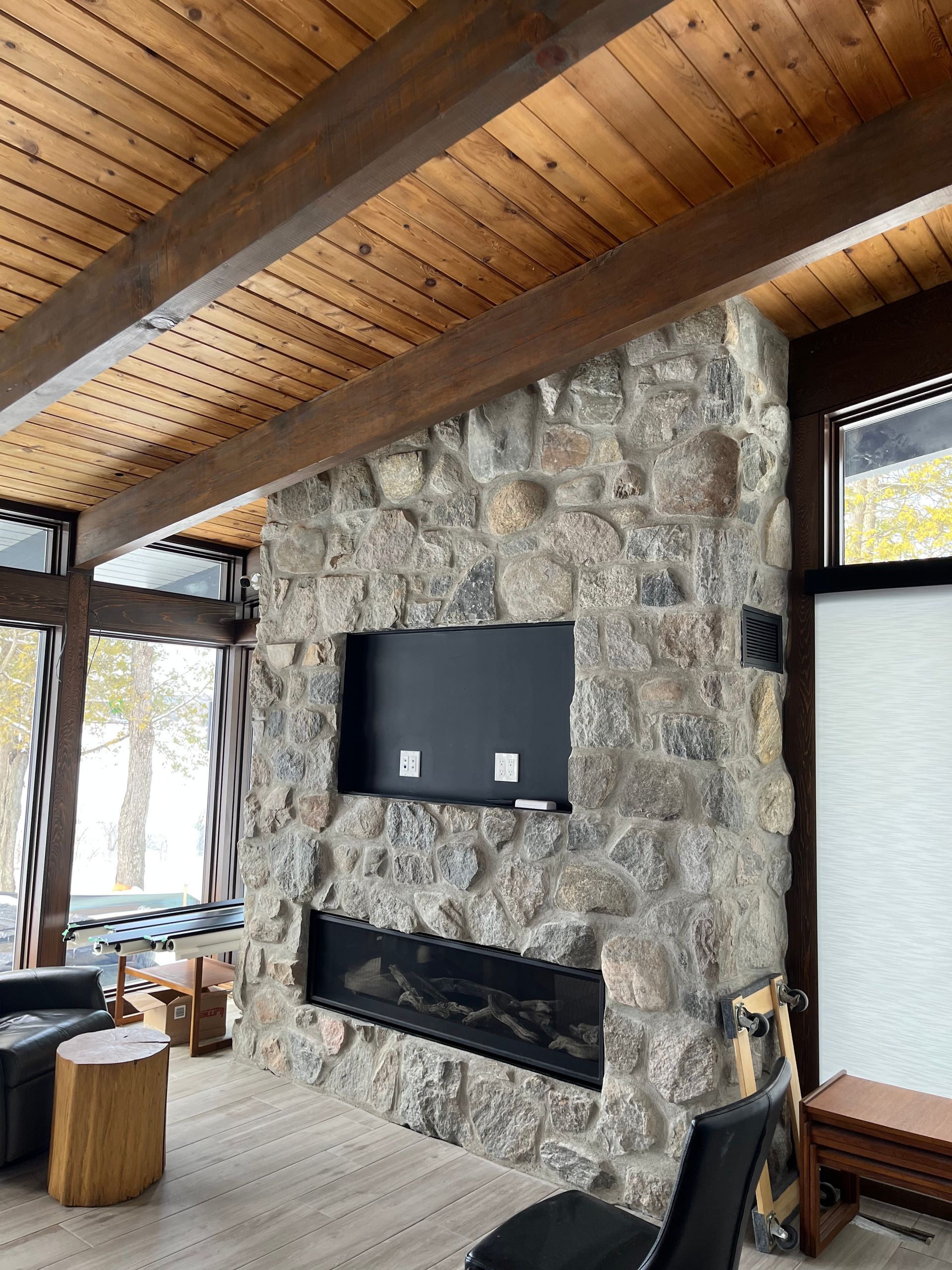 Un séjour avec une cheminée en pierre et un plafond en bois.