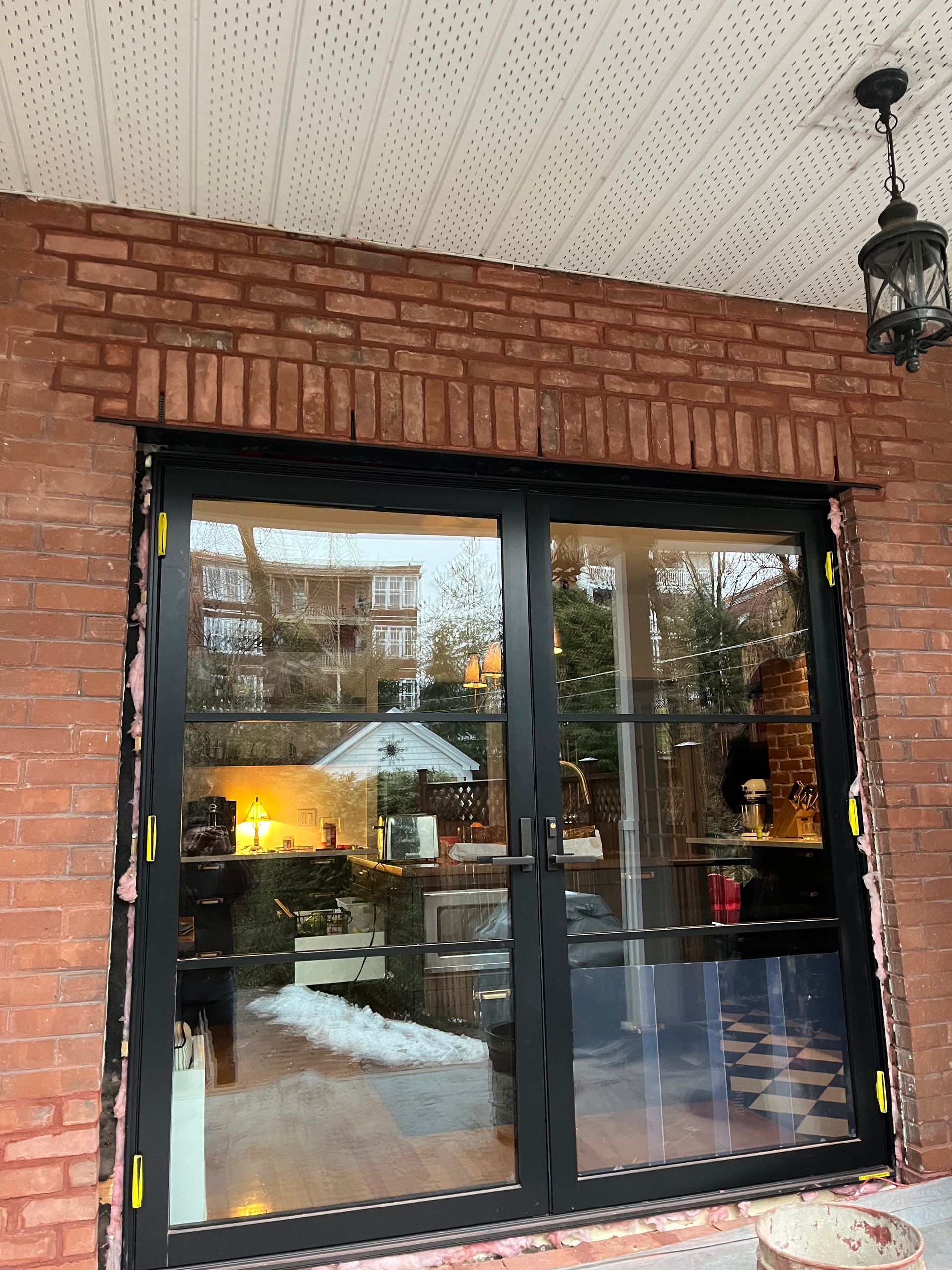 Une porte coulissante en verre est en cours d'installation sur un mur de briques.