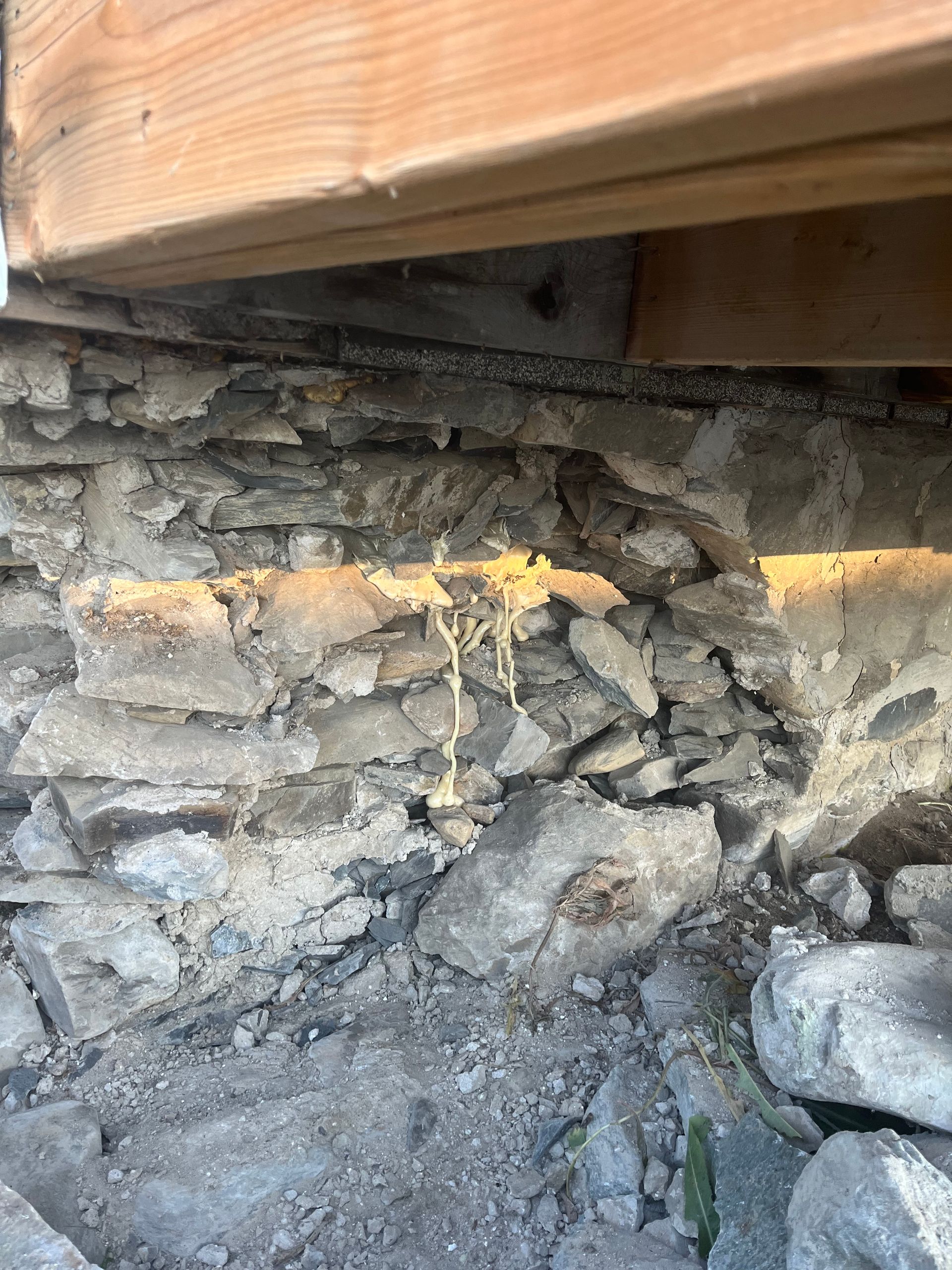 Un gros plan d'un mur de pierre sous une structure en bois.