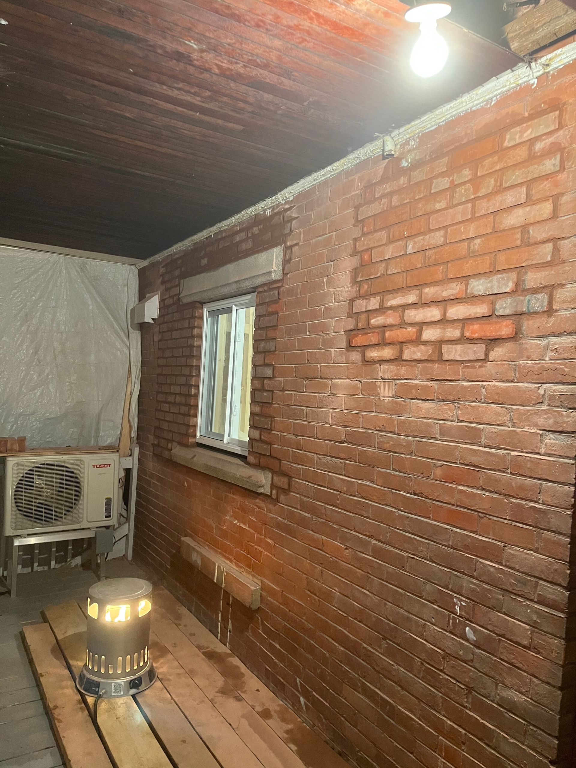 Une pièce avec un mur de briques et une fenêtre.
