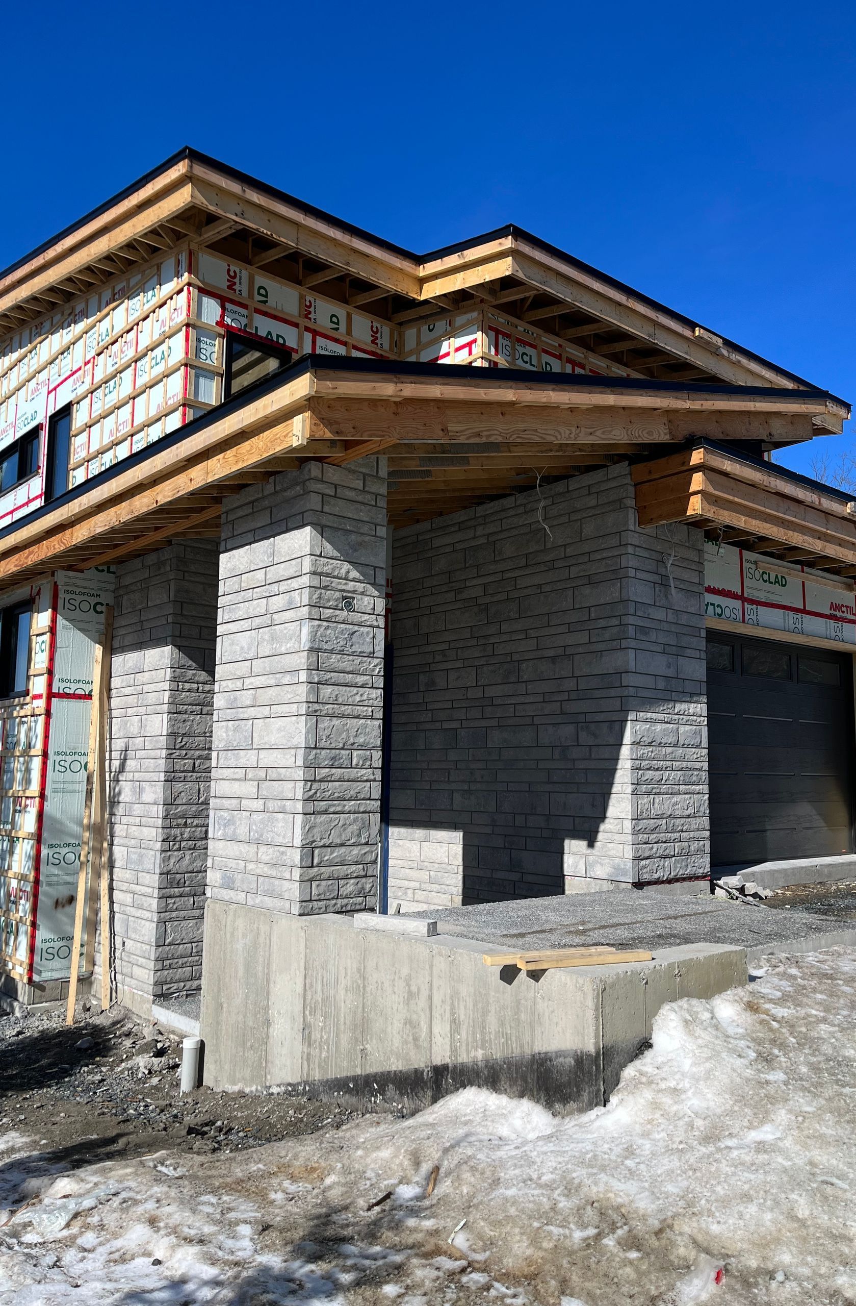 Une maison est en construction dans la neige avec un ciel bleu en arrière-plan.