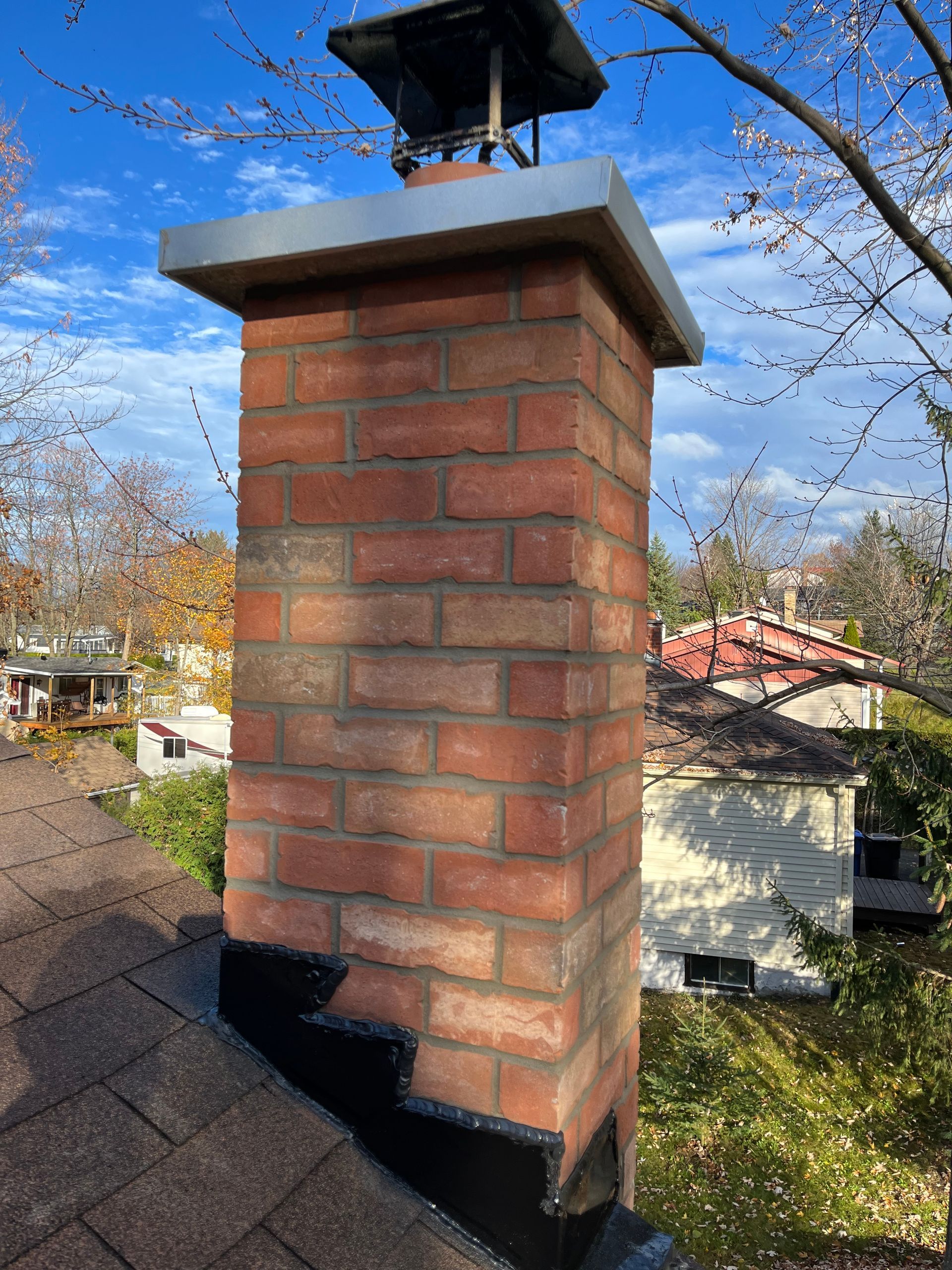 Une cheminée en brique se trouve au sommet d’un toit.