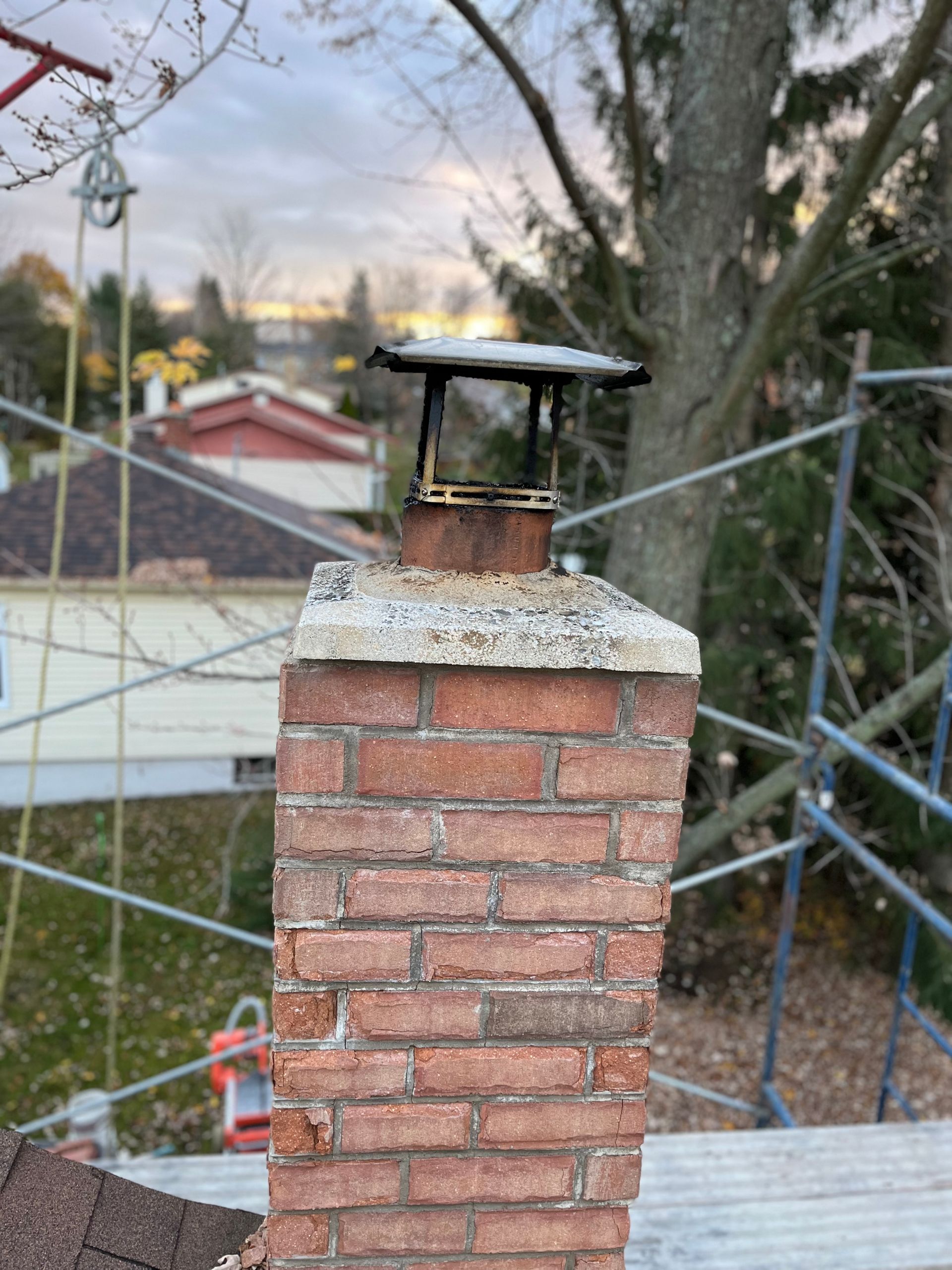 Une cheminée en brique se trouve au sommet d’un toit.