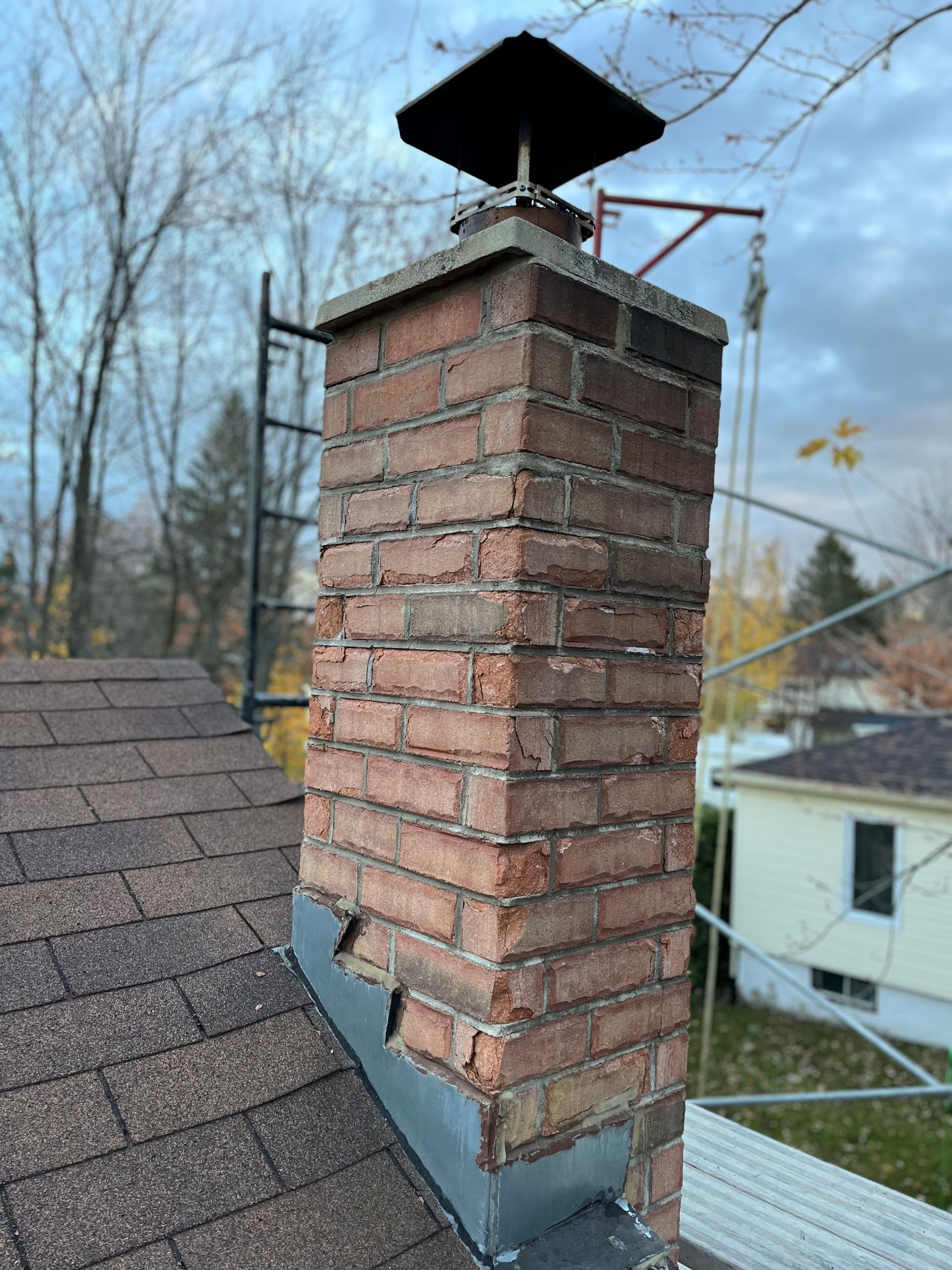 Une cheminée en brique se trouve au sommet d’un toit.