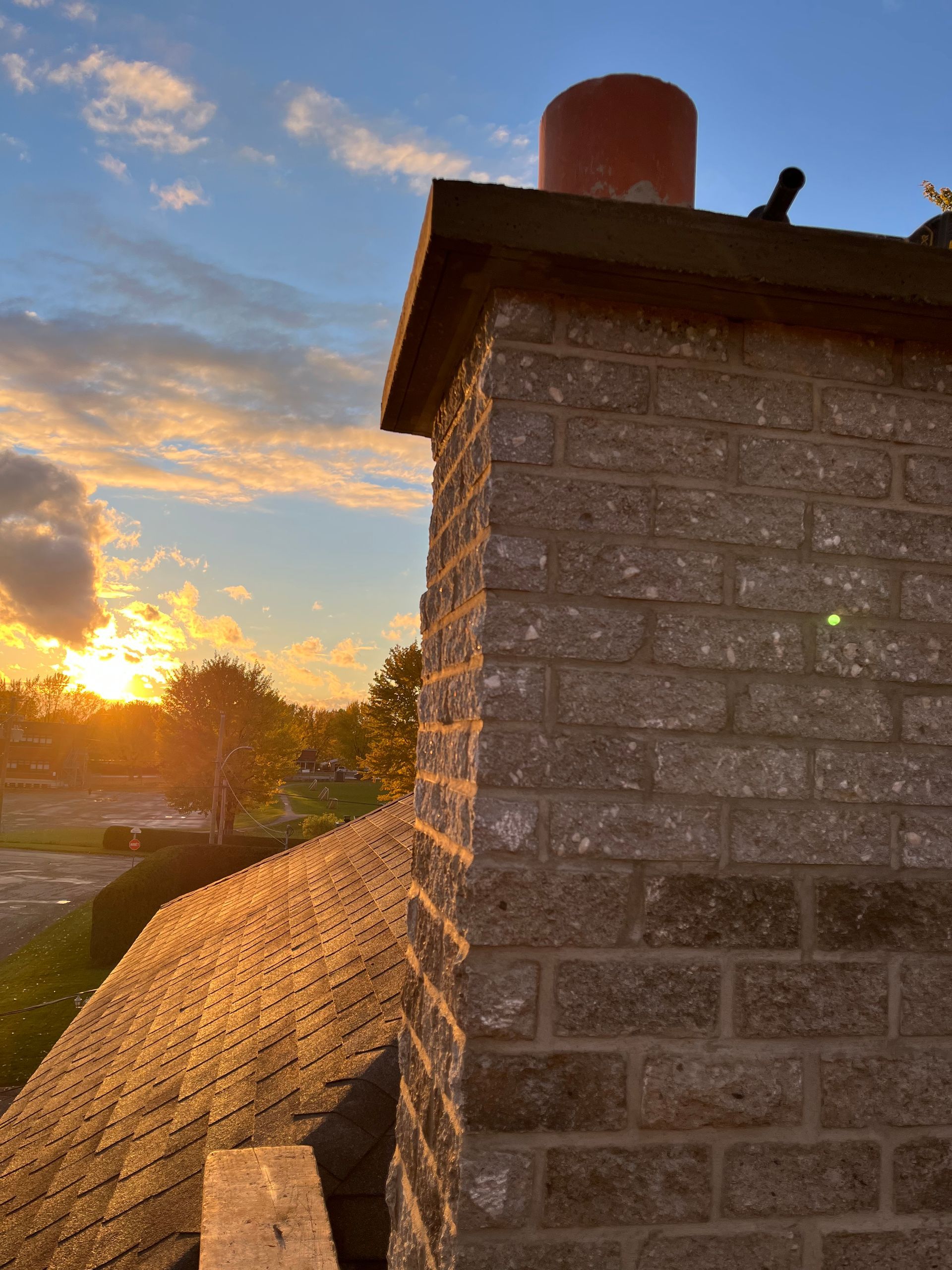 Une cheminée en brique avec un coucher de soleil en arrière-plan