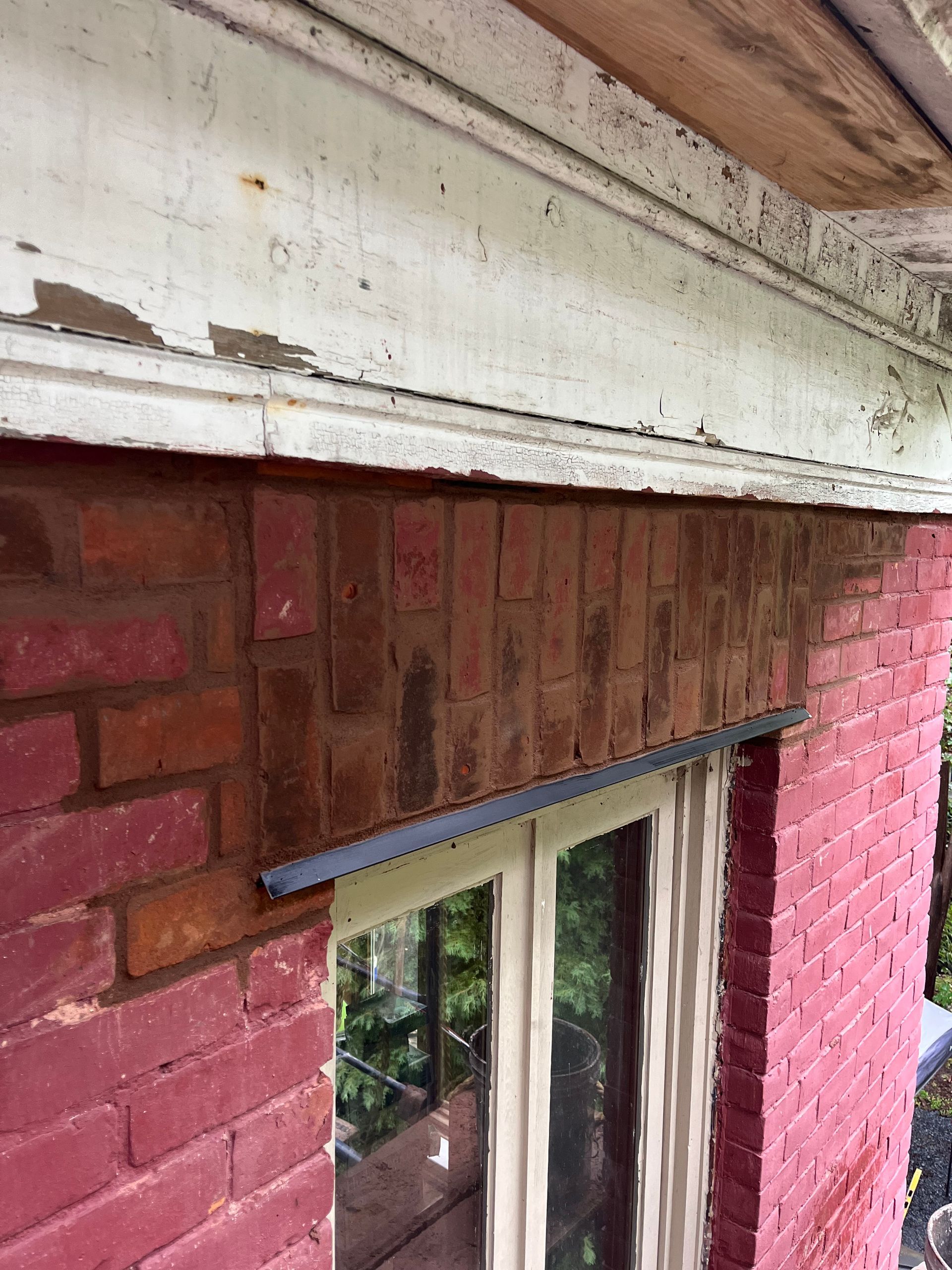 Un bâtiment en brique rouge avec une fenêtre blanche et une bordure blanche.