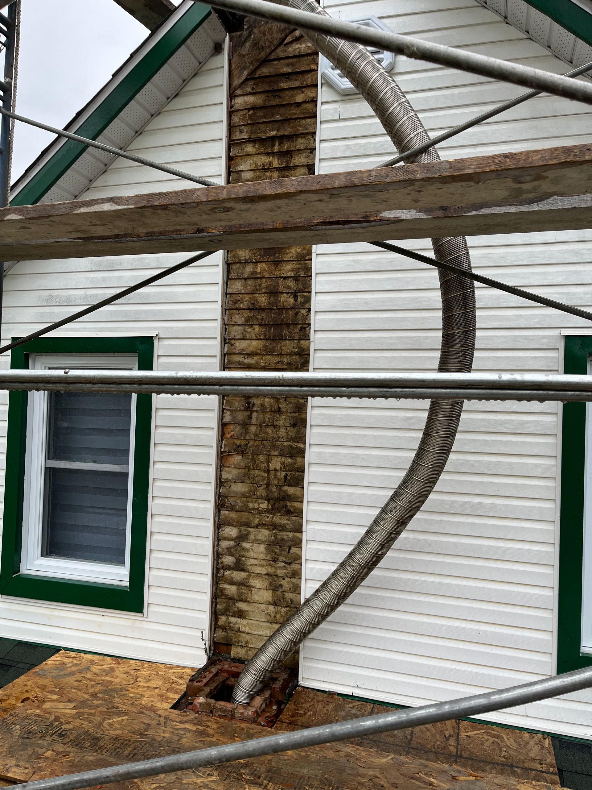 Une maison avec une cheminée sur le côté et un échafaudage autour.