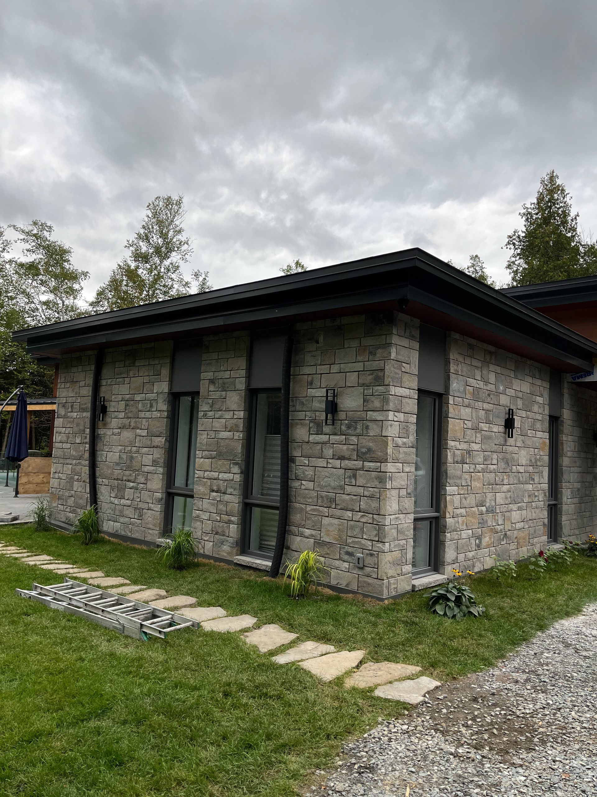 Une petite maison en brique avec de nombreuses fenêtres se trouve au sommet d’une pelouse verdoyante.