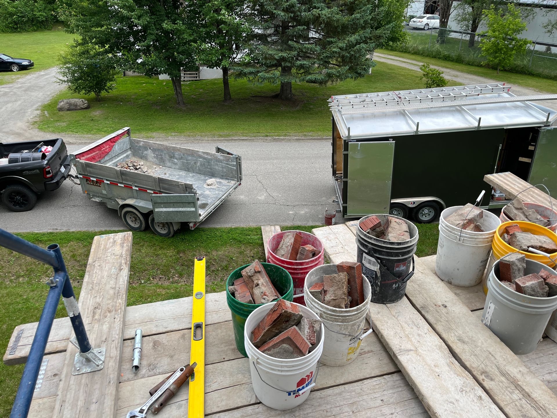Des seaux de briques sont posés sur une table en bois à côté d’une benne à ordures.