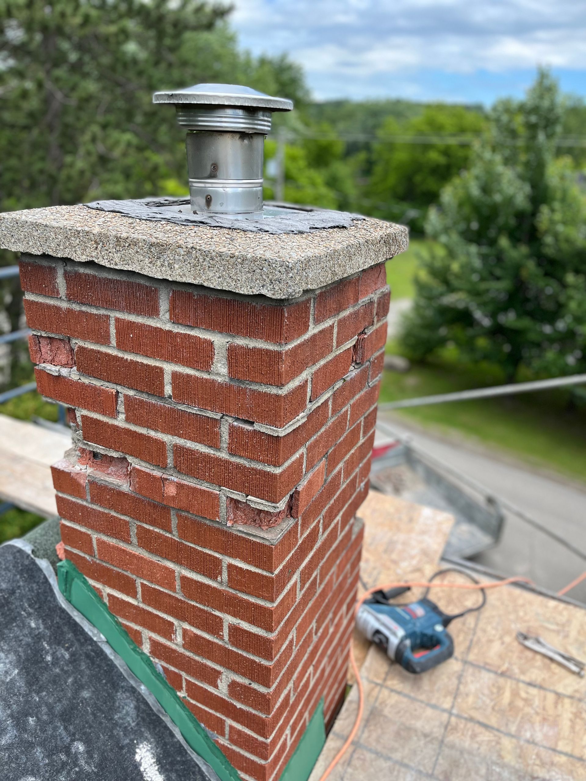 Une cheminée en brique se trouve au sommet d’un toit.