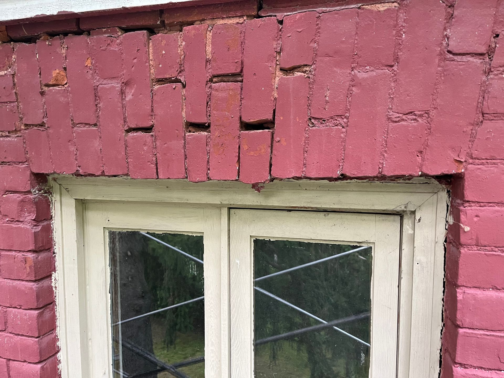 Une fenêtre sur un mur de briques rouges avec un cadre blanc.