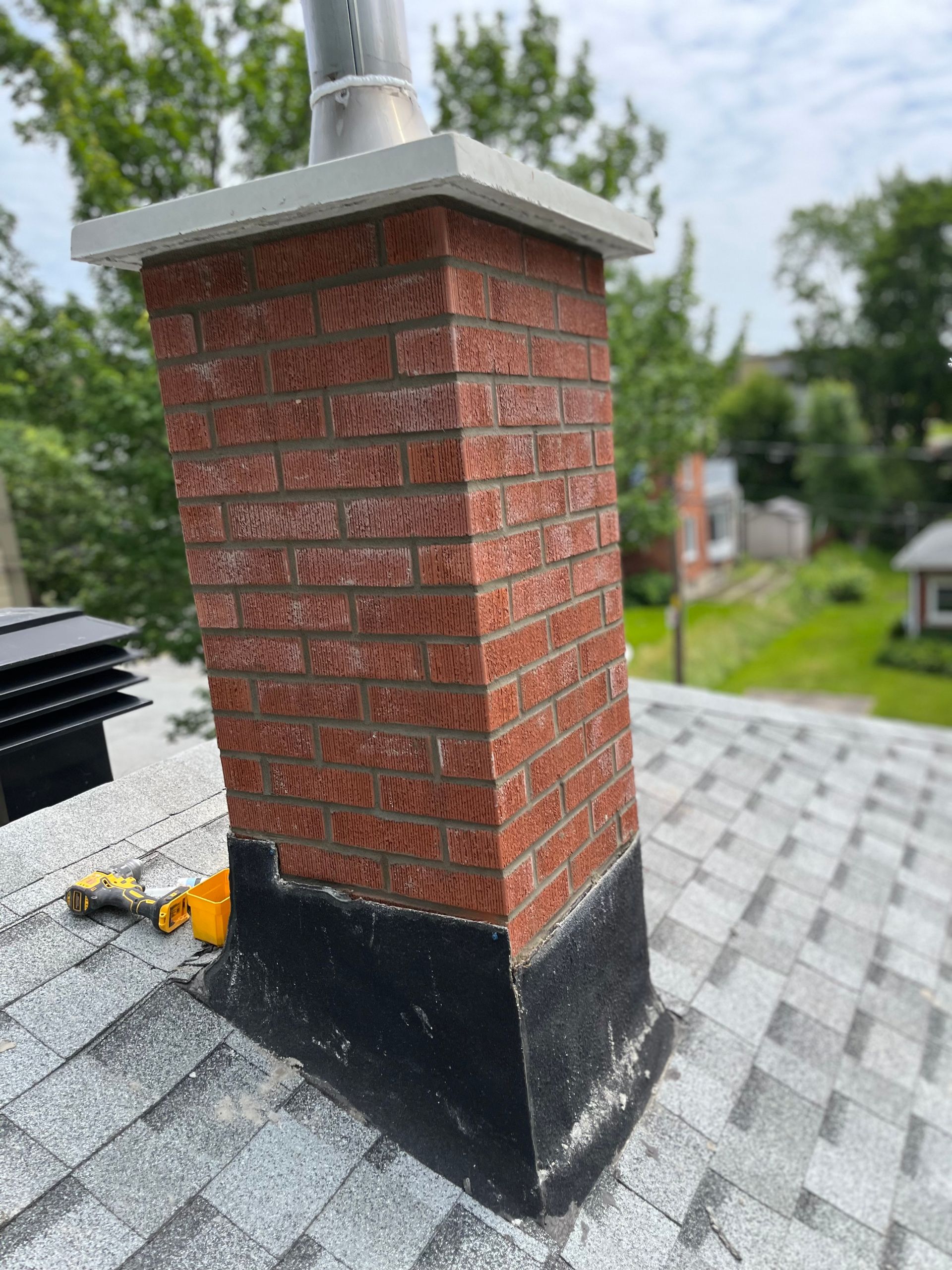 Une cheminée en brique se trouve au sommet d’un toit.