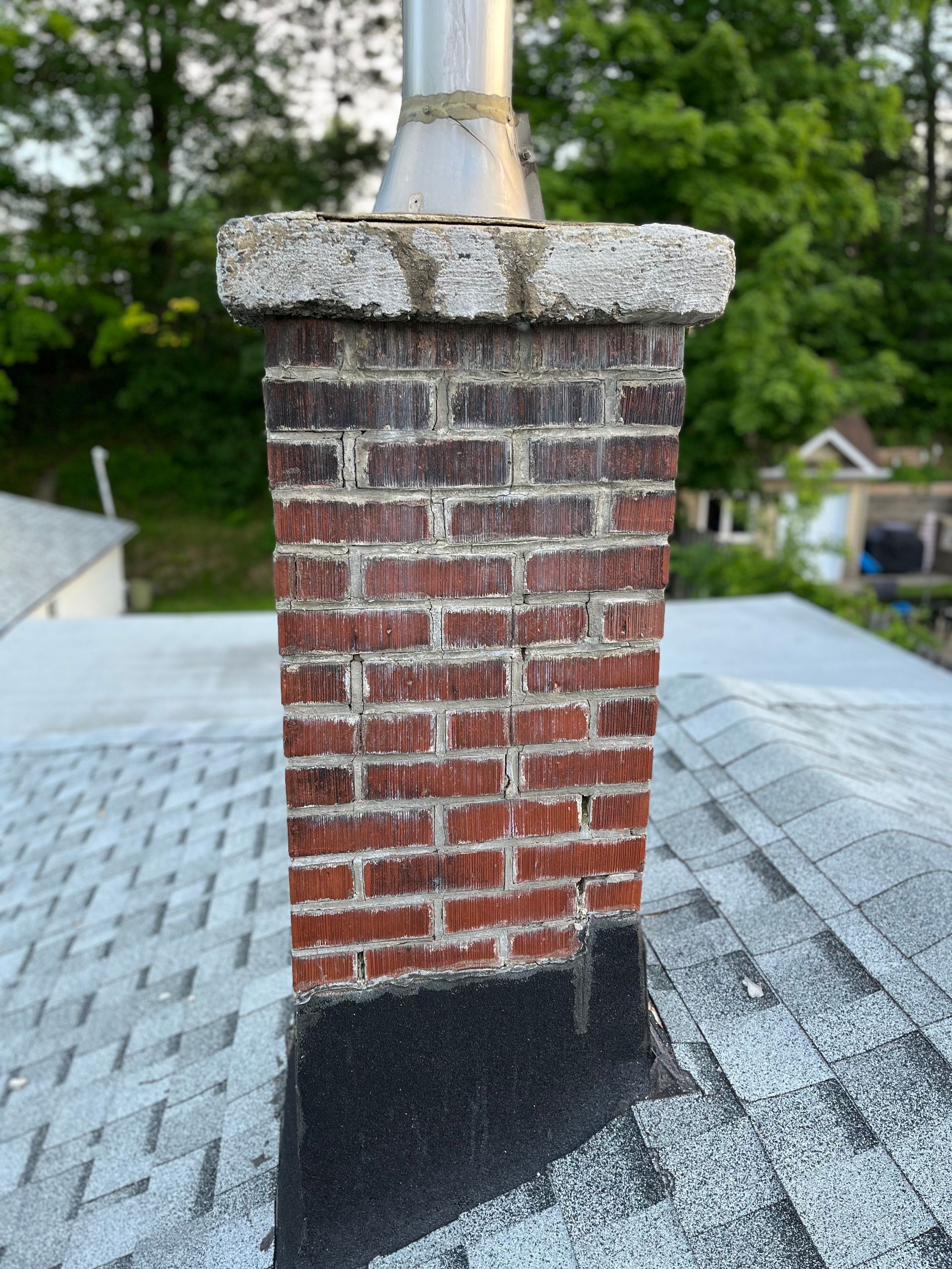 Une cheminée en brique se trouve au sommet d’un toit.