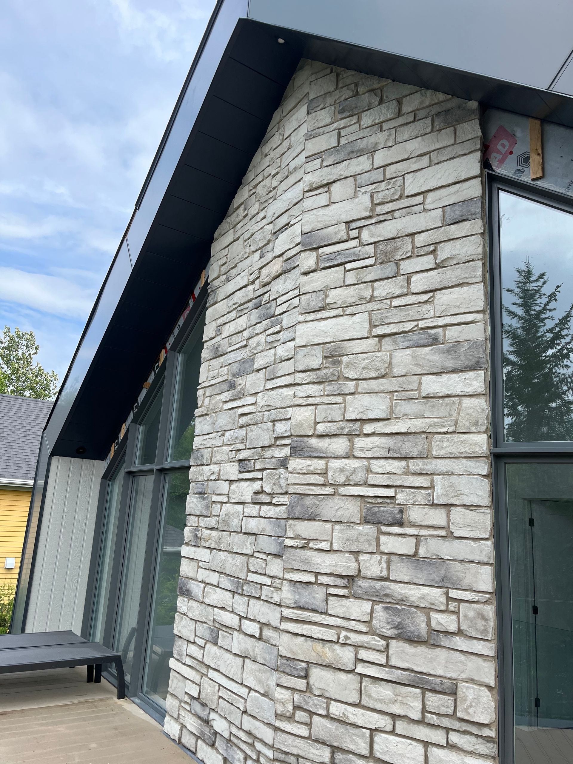 Le côté d’une maison avec un mur de briques et beaucoup de fenêtres.