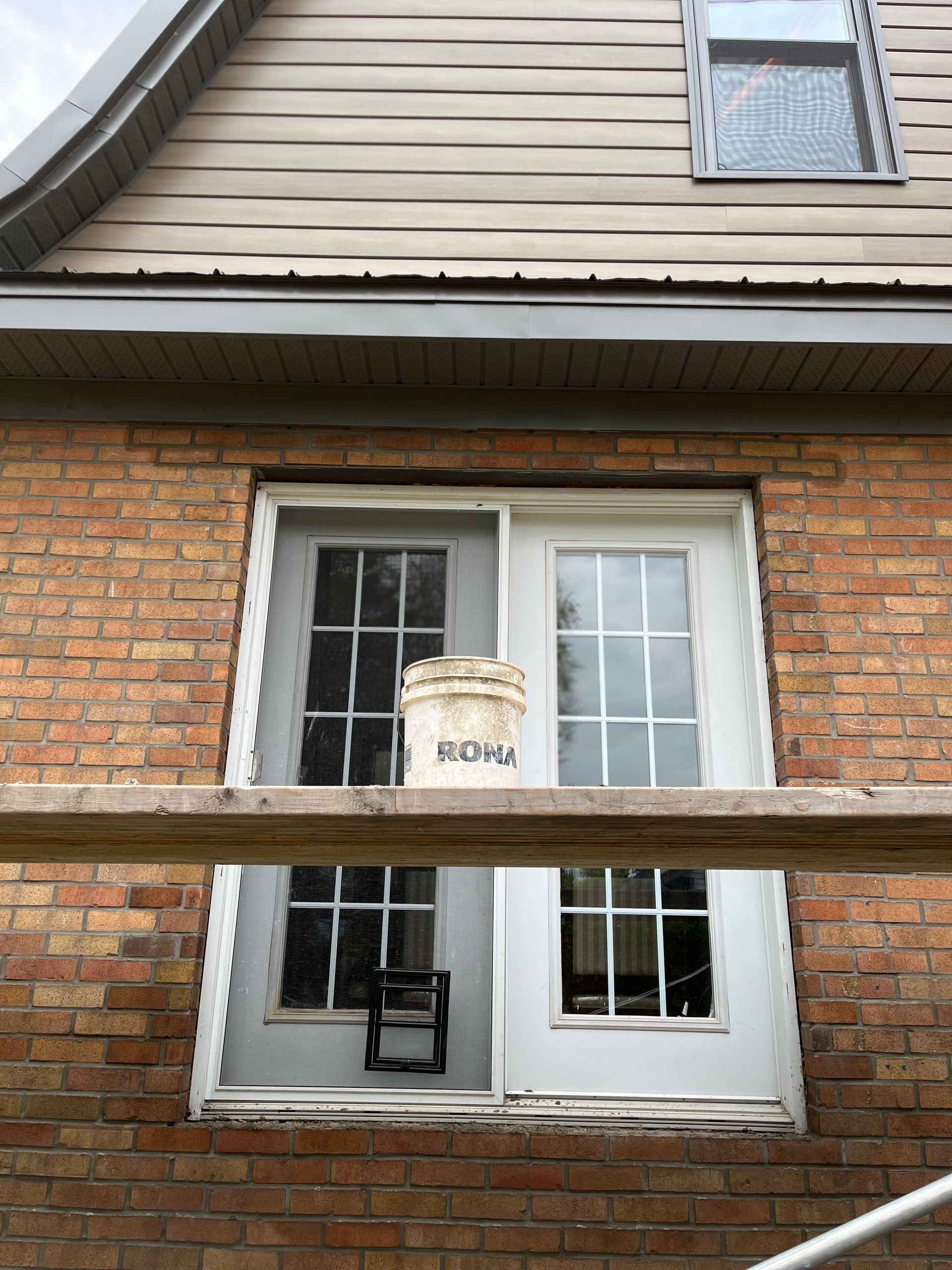 Une maison en brique avec une fenêtre et un seau sur le rebord de la fenêtre.
