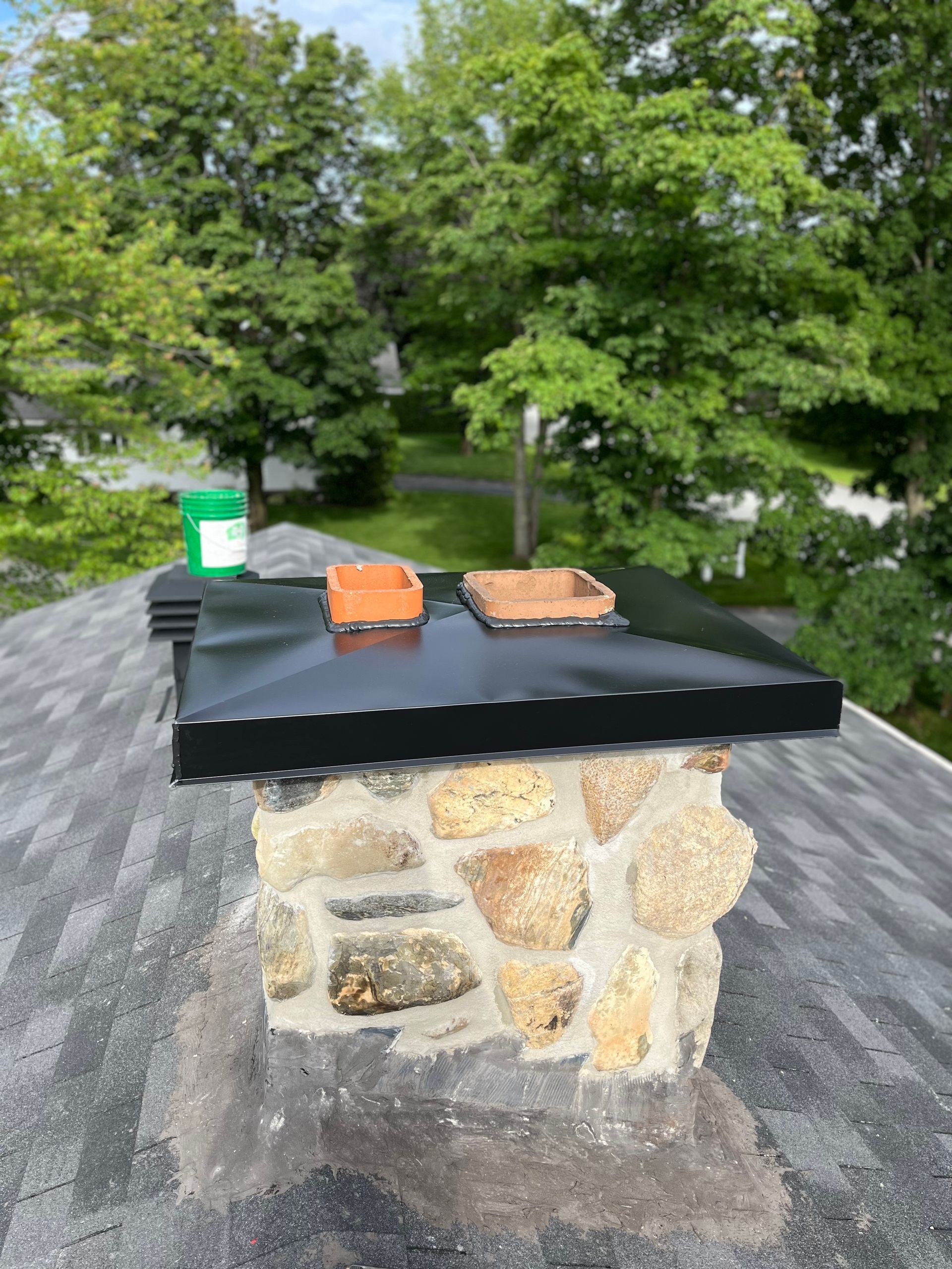 Une cheminée au sommet d’un toit avec des arbres en arrière-plan.