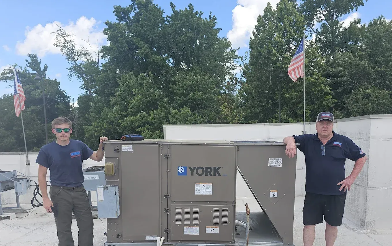 Two men are standing next to a york air conditioner.