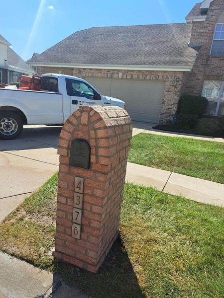 Brick mailbox with house number 4325 in front of a house with a white pickup truck parked nearby.