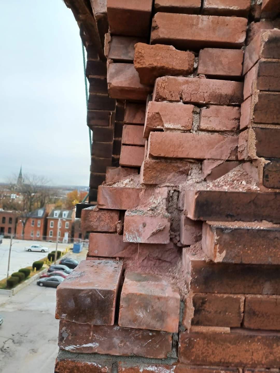 Close-up of a crumbling brick building facade with severely damaged bricks. The bricks are red, and some are broken or displaced.