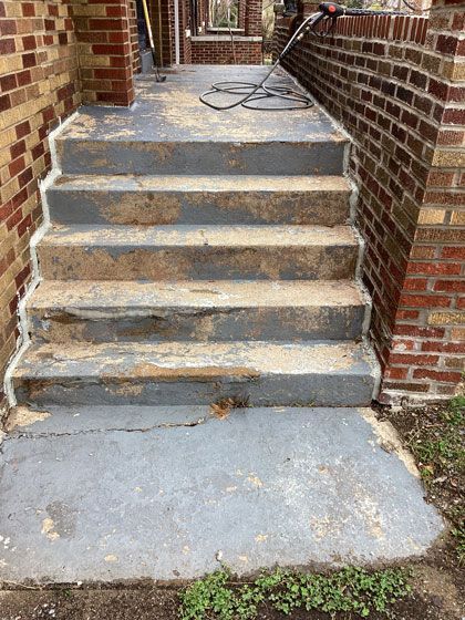 Concrete front steps with peeling gray paint and visible wear, leading up to a brick house entrance.